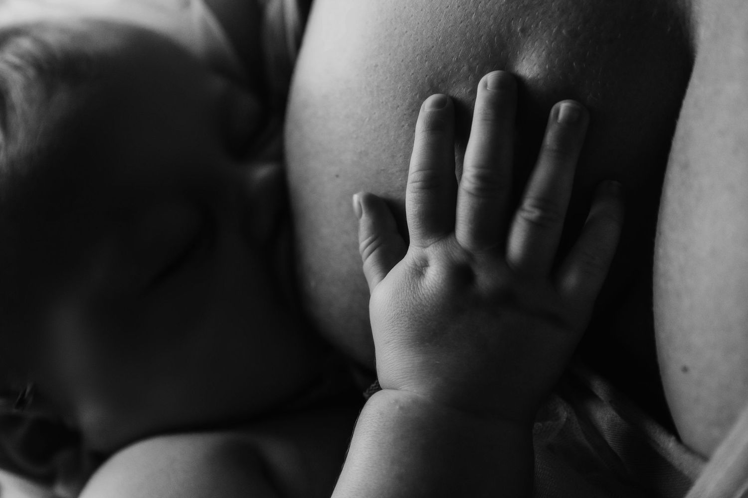 Black and white close-up of a small baby hand against soft background.