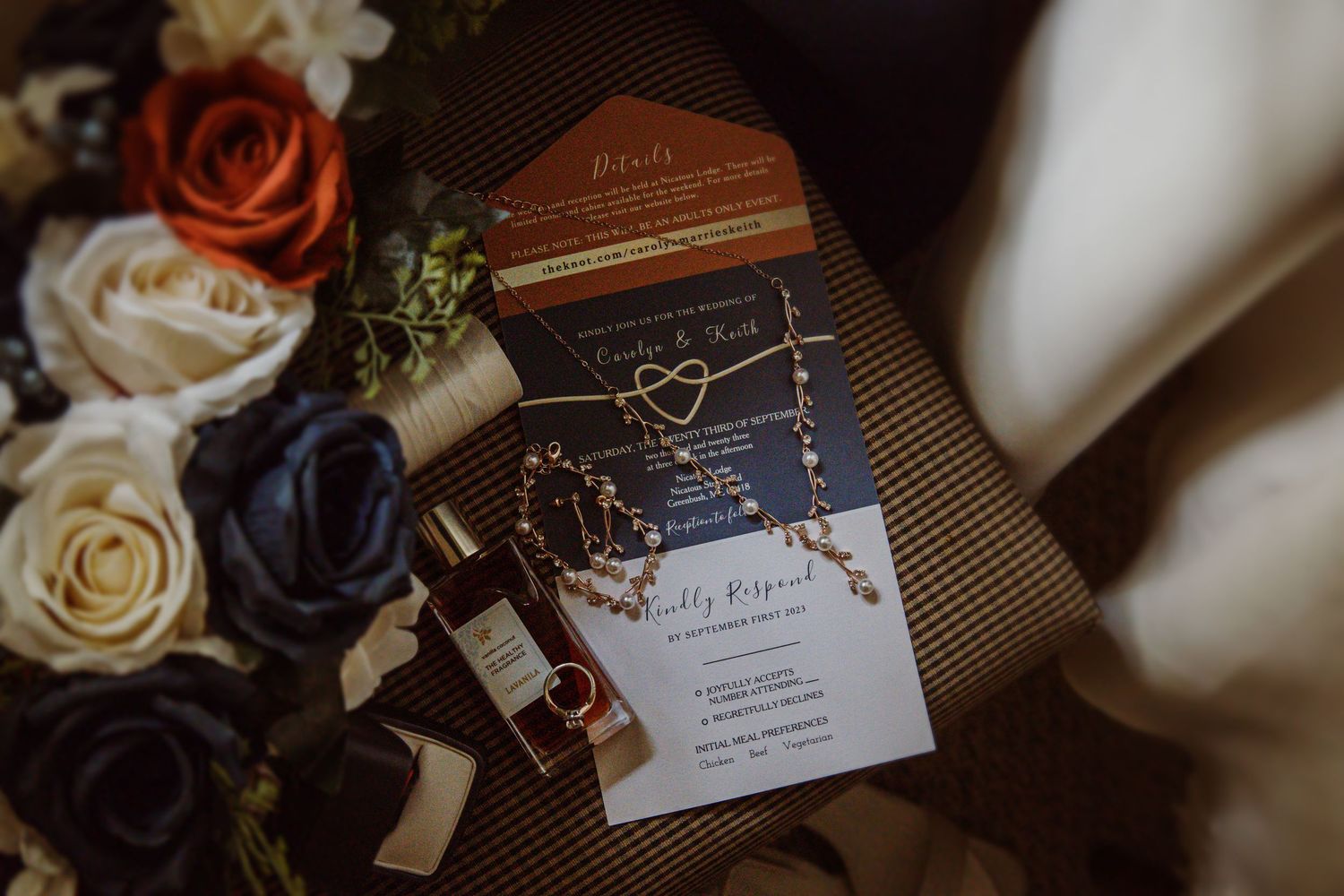 Wedding invitation and floral arrangement with roses in muted tones on a textured surface.