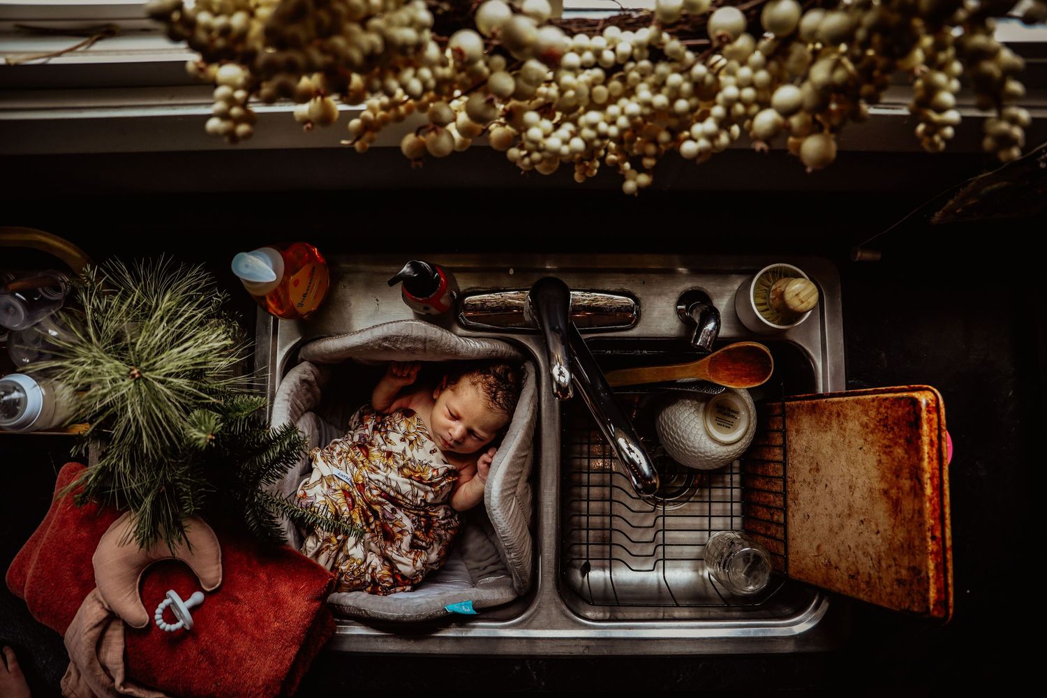 Overhead view of a kitchen sink with holiday decorations and soap bubbles in warm lighting.