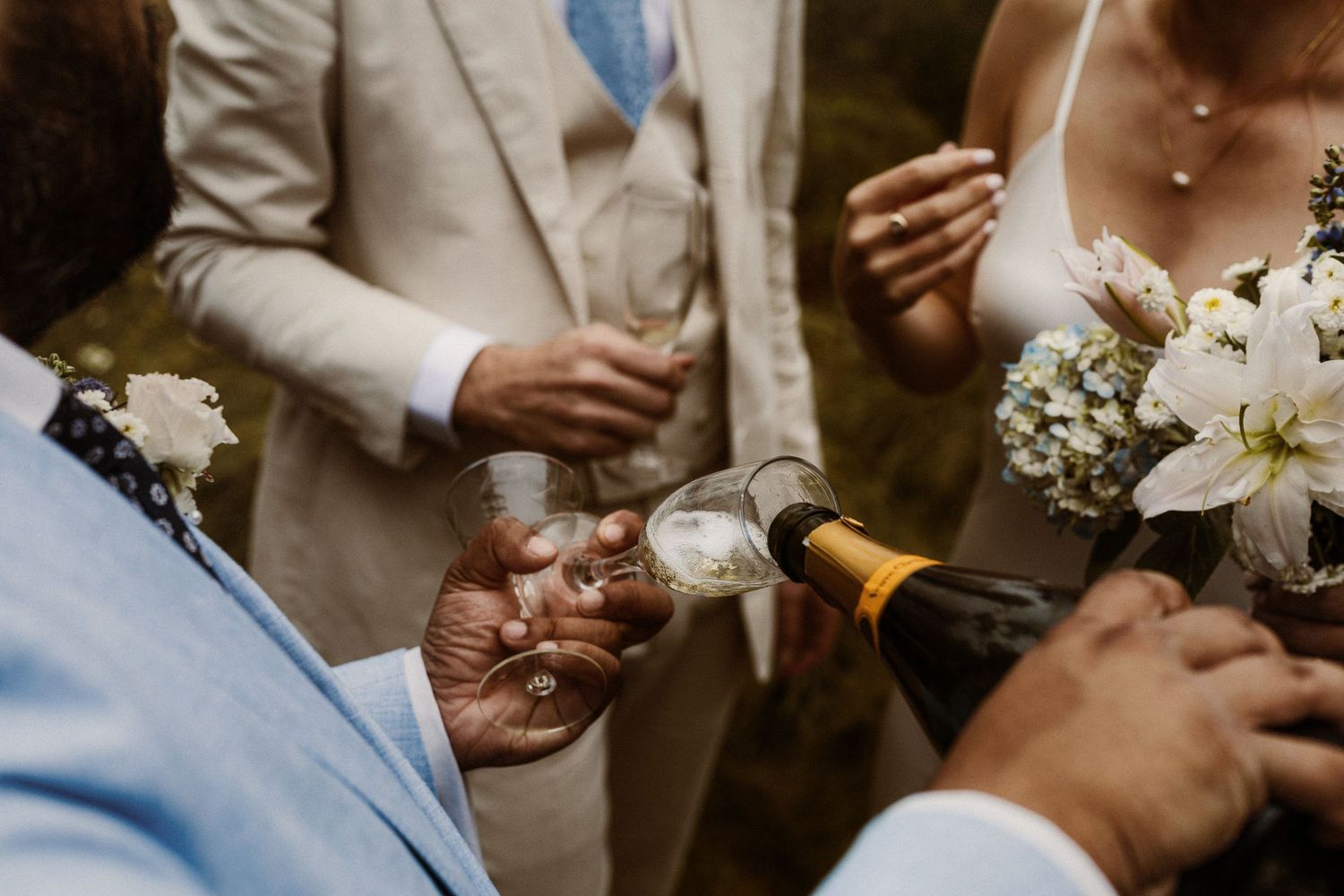 Wedding guests toasting with champagne glasses during an elegant outdoor celebration.