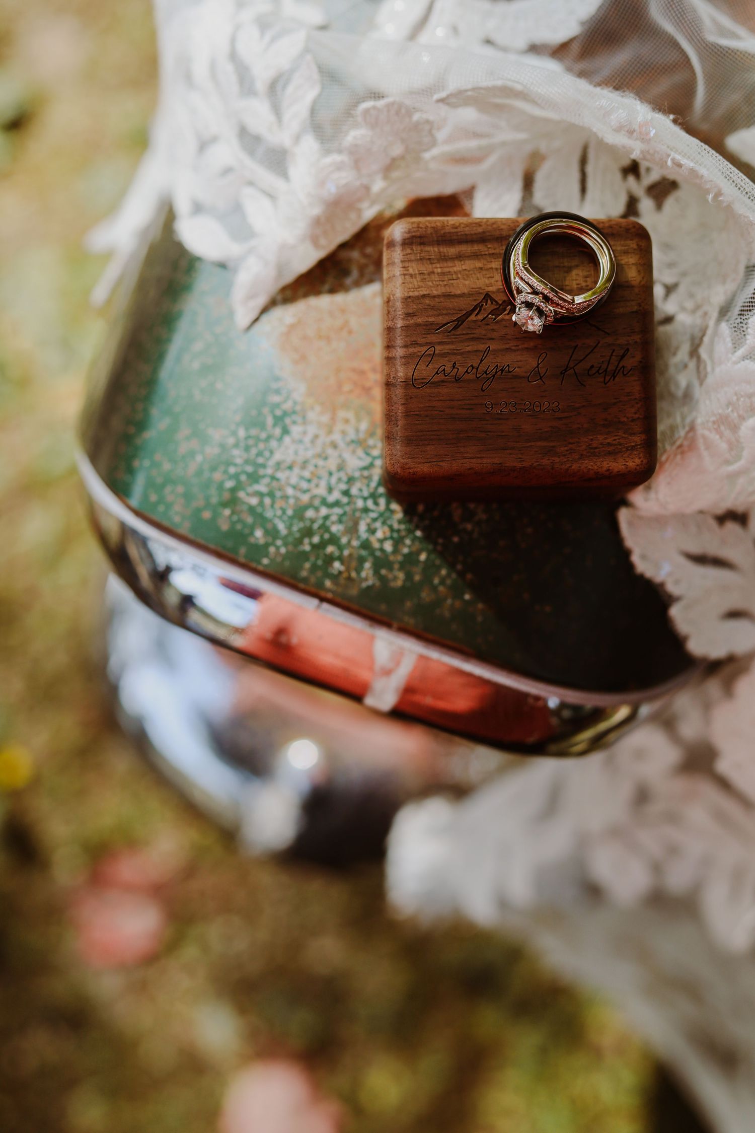 Wedding rings displayed on a wooden box with delicate lace details.