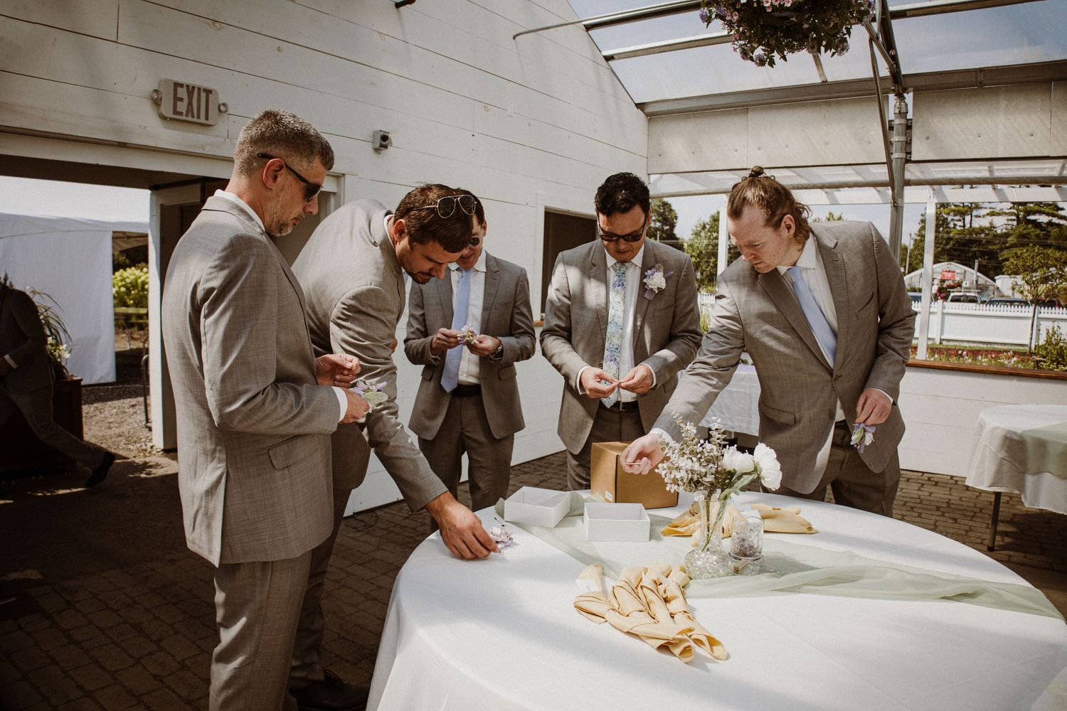 Guests in gray suits gathered around a table with appetizers at an outdoor event.