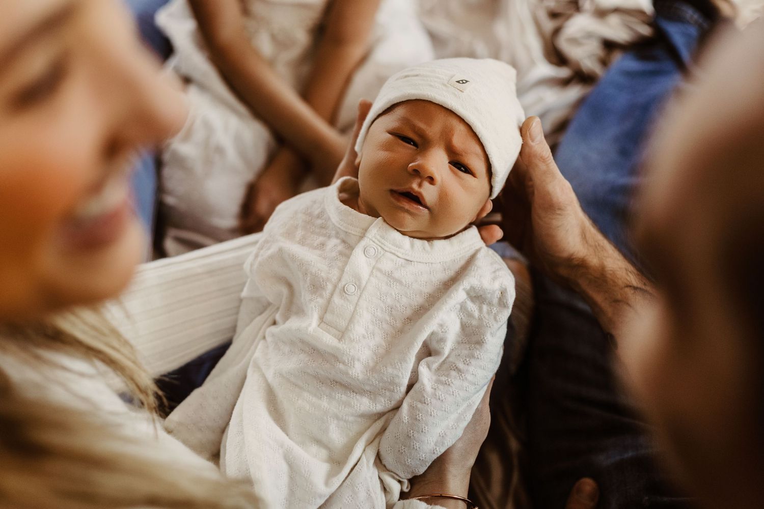 A baby in white christening or baptism clothing lies peacefully during a religious ceremony.