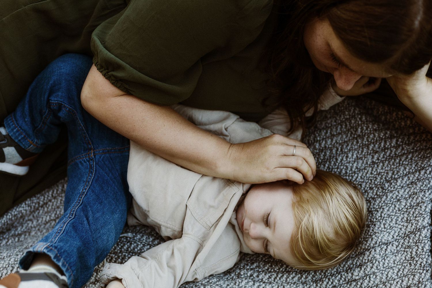 Tender moment captured indoors on a grey carpet in natural light.