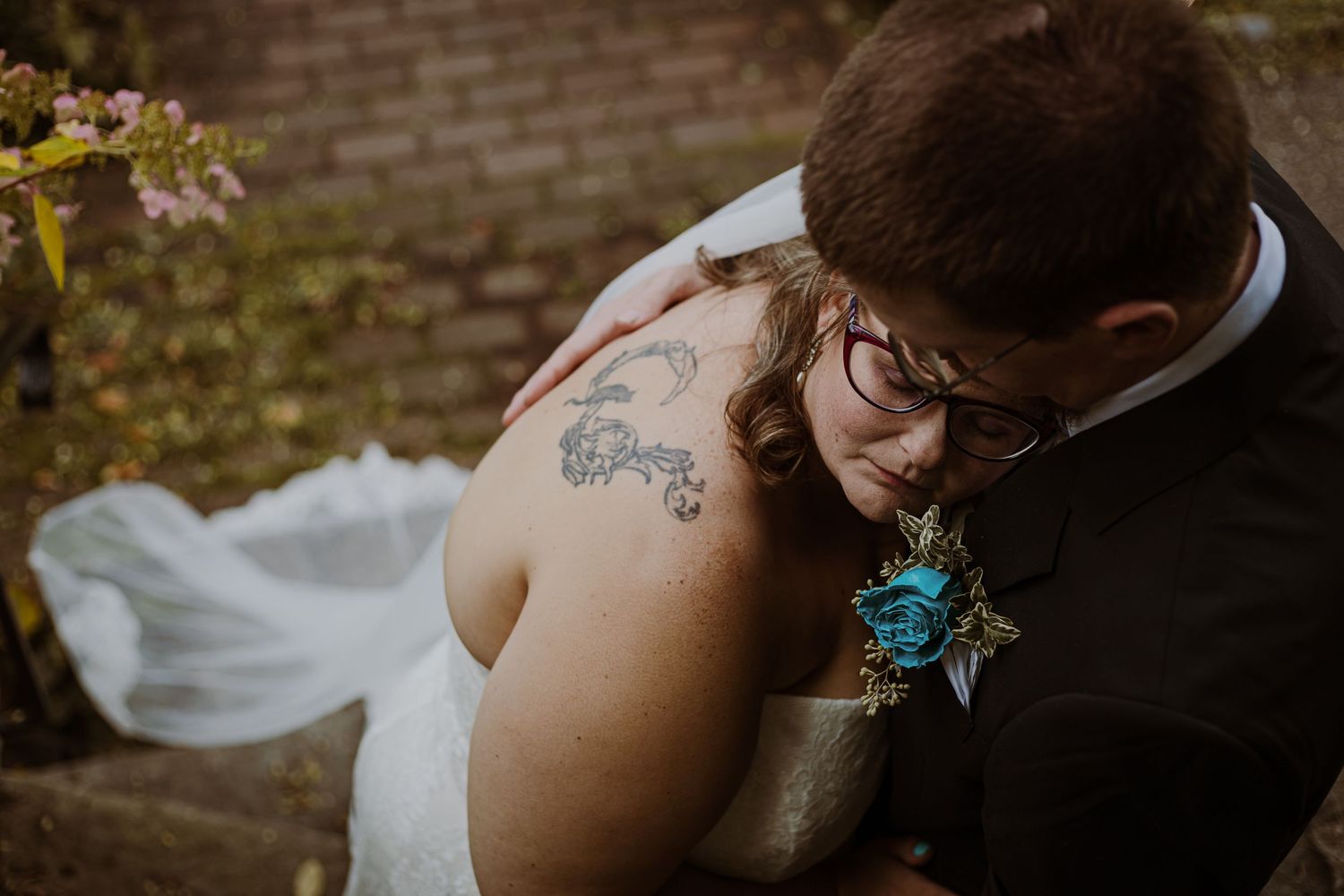 Intimate moment between newlyweds showing teal boutonniere and detailed dress.