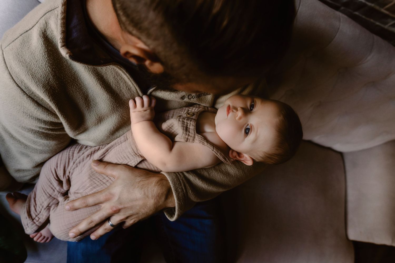 Parent tenderly holding newborn baby in intimate indoor portrait.