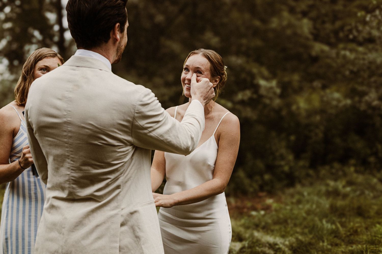 An emotional moment during a wedding ceremony in an outdoor garden setting.