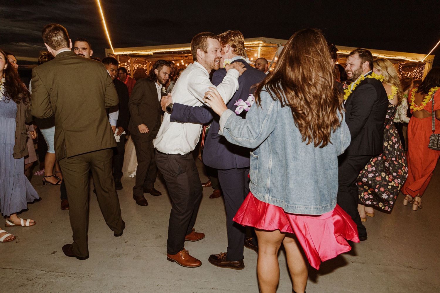 Lively dance party scene with people dancing under outdoor evening lighting.