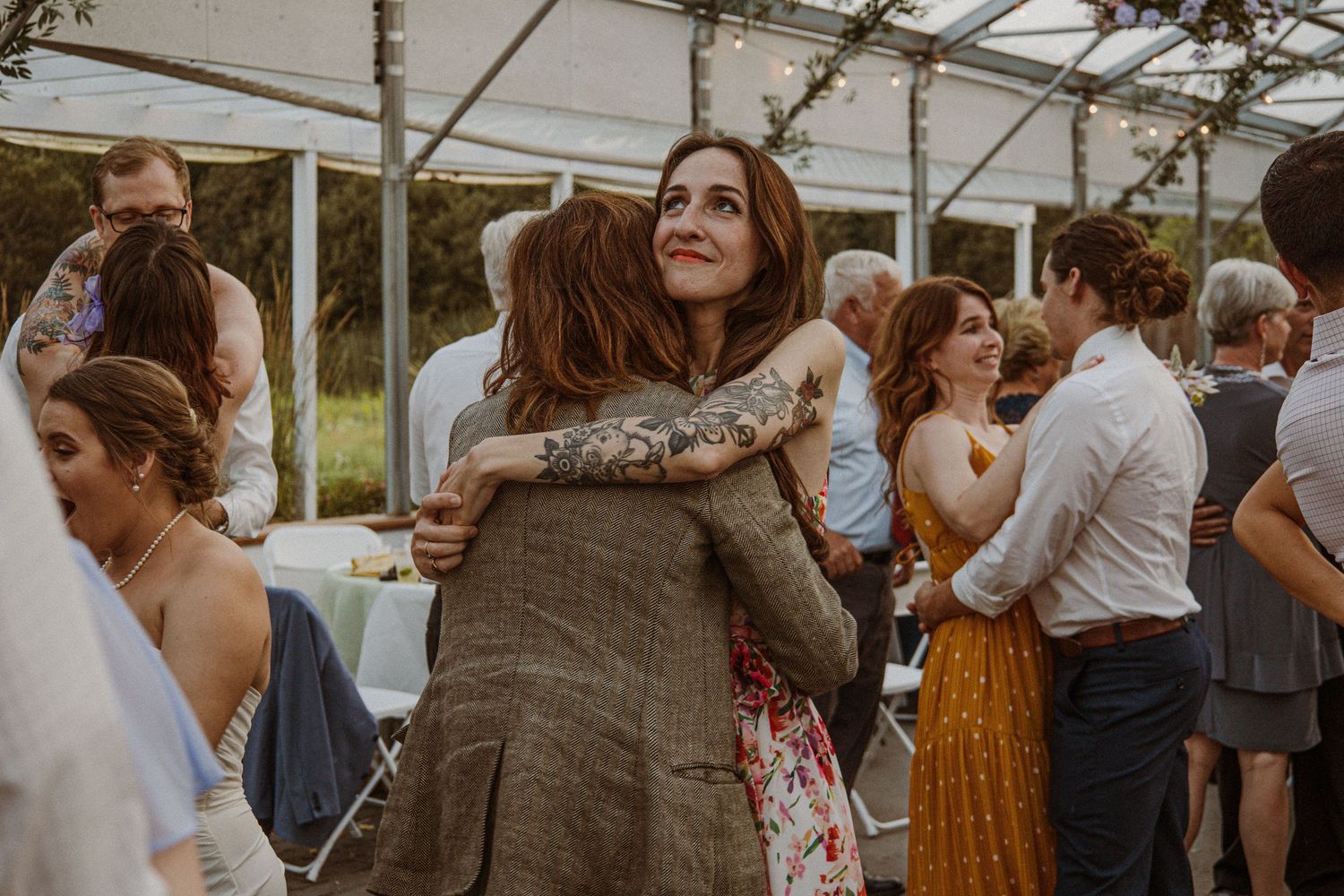 Wedding reception guests mingling and embracing at an outdoor venue.