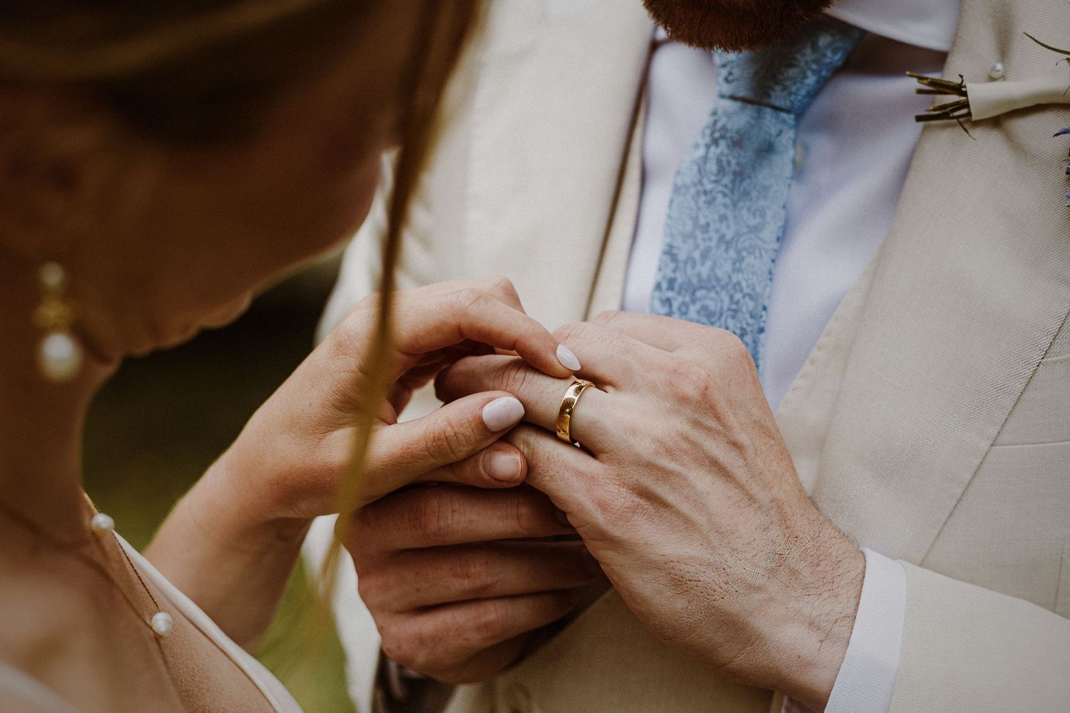 Close-up of hands exchanging rings during a wedding ceremony.