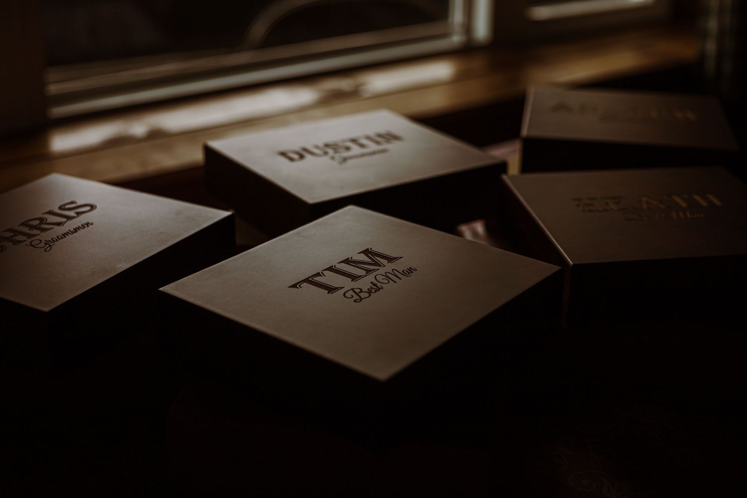 Wedding stationery cards arranged in moody lighting on dark surface.