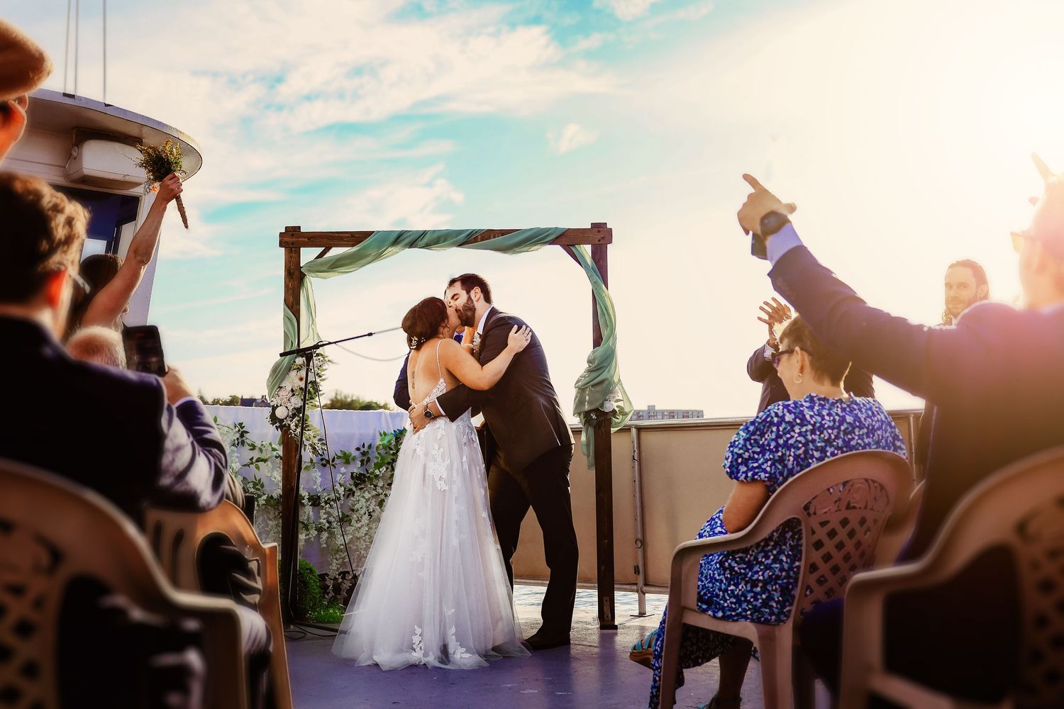 Waterfront wedding ceremony during golden hour with guests celebrating.