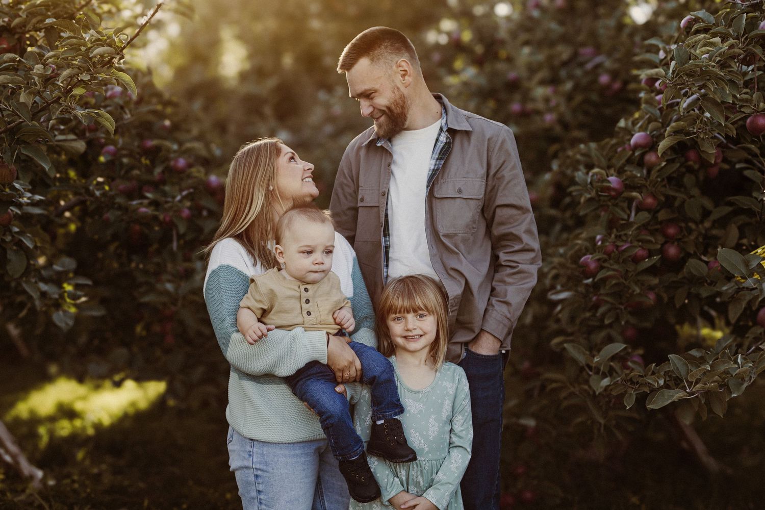 Heartwarming family portrait of four people embracing outdoors in natural lighting.