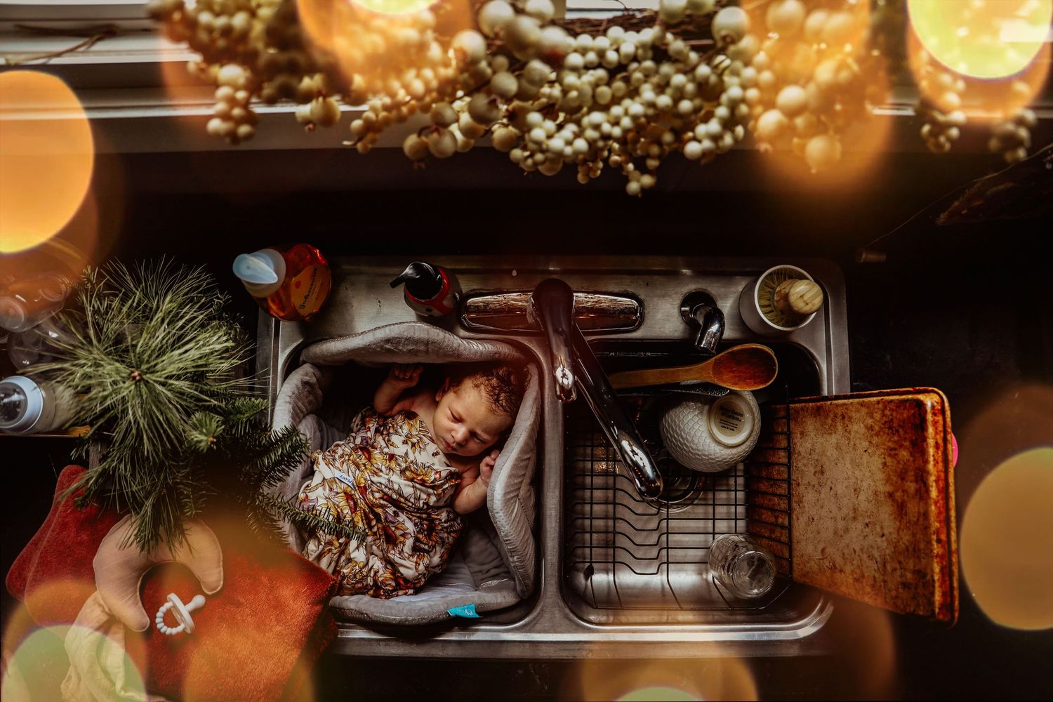 Overhead view of a kitchen sink with warm glowing lights and holiday decorations visible above.