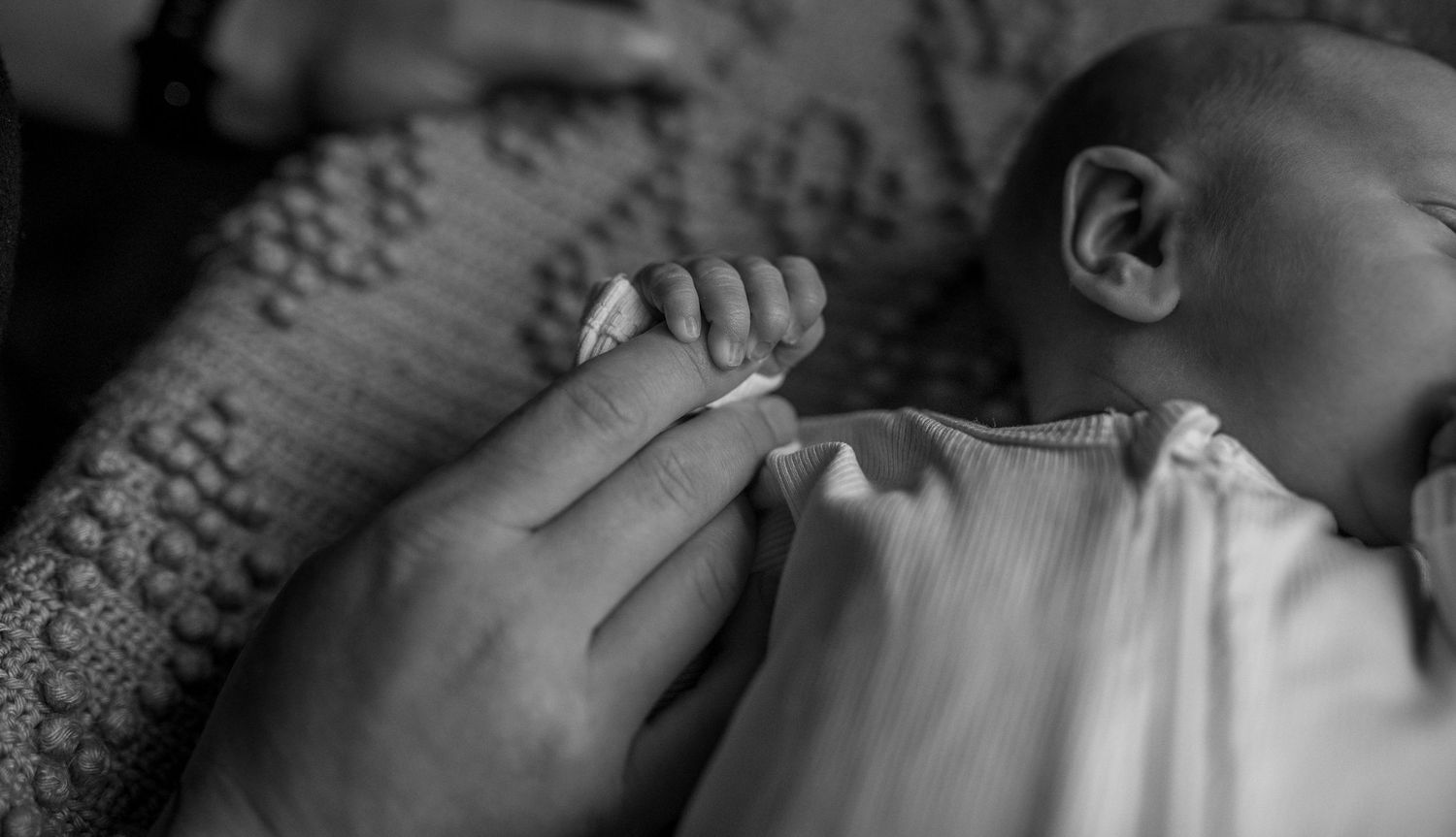 newborn holding mothers hand