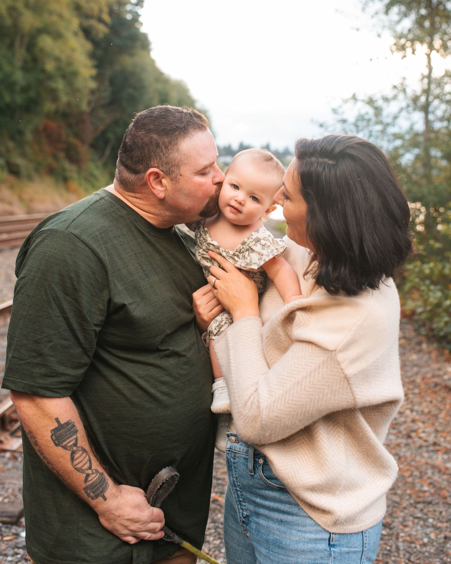 mom, dad and toddler daughter snuggled up during outdoor family session