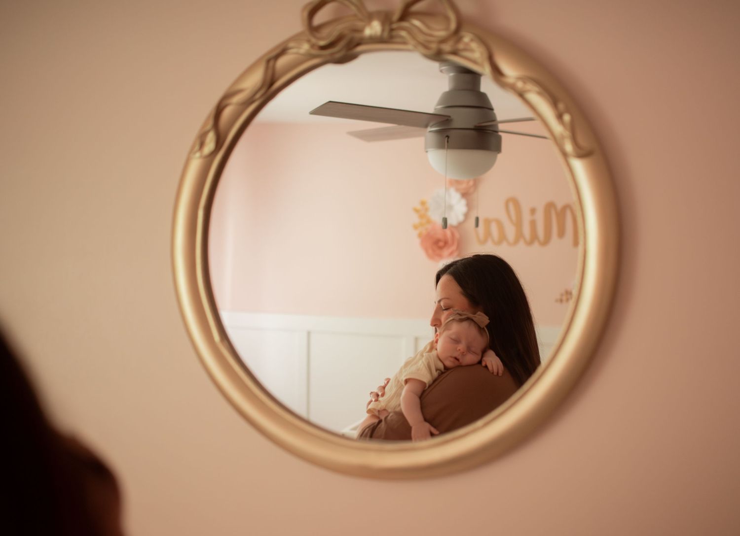 mother and newborn in nursery looking through mirror