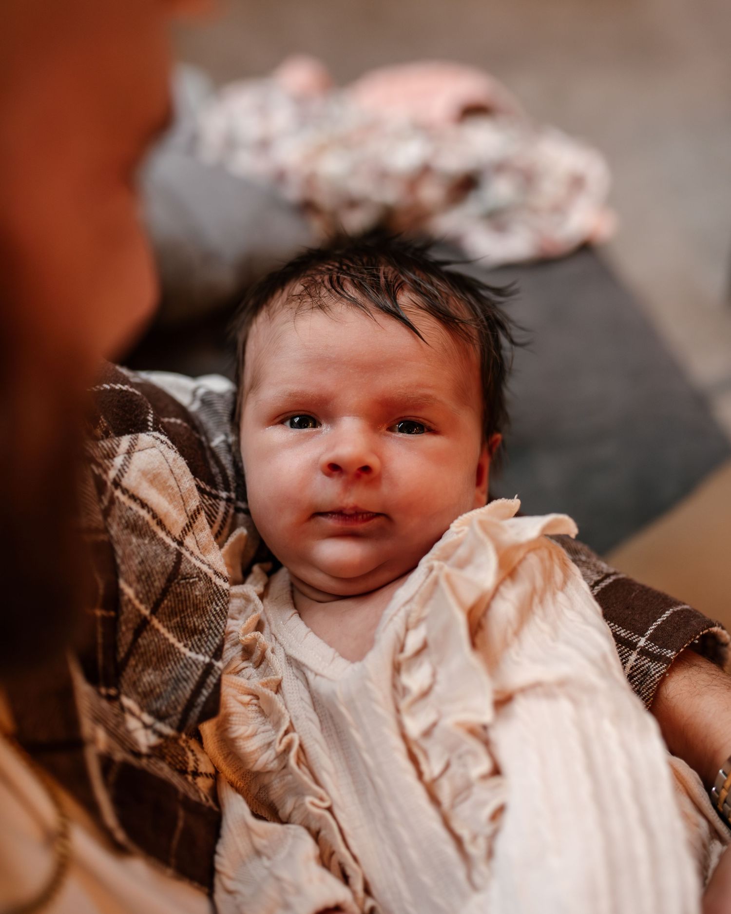A newborn baby girl looking at the camera while dad is holding her