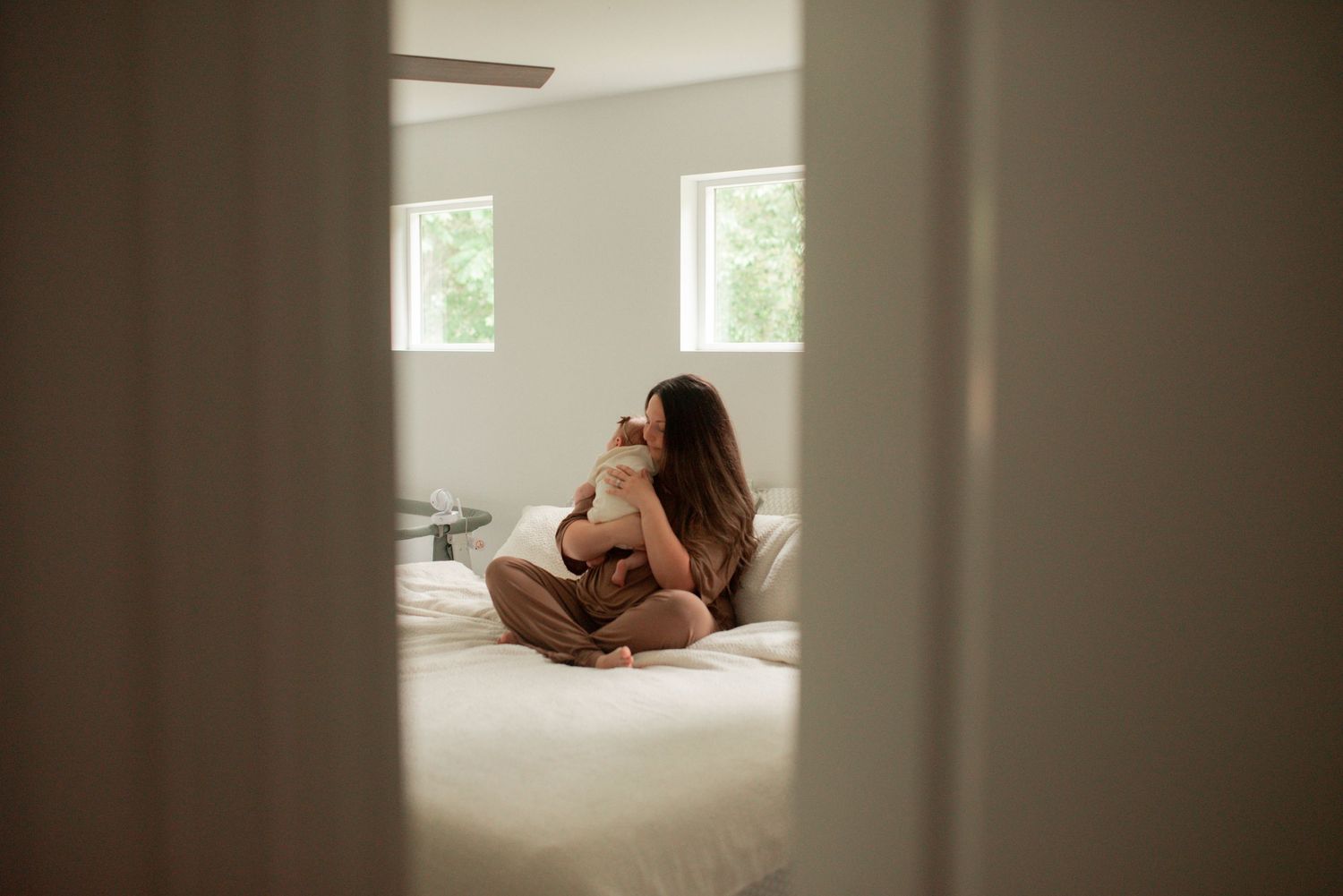 mother sitting on bed holding newborn
