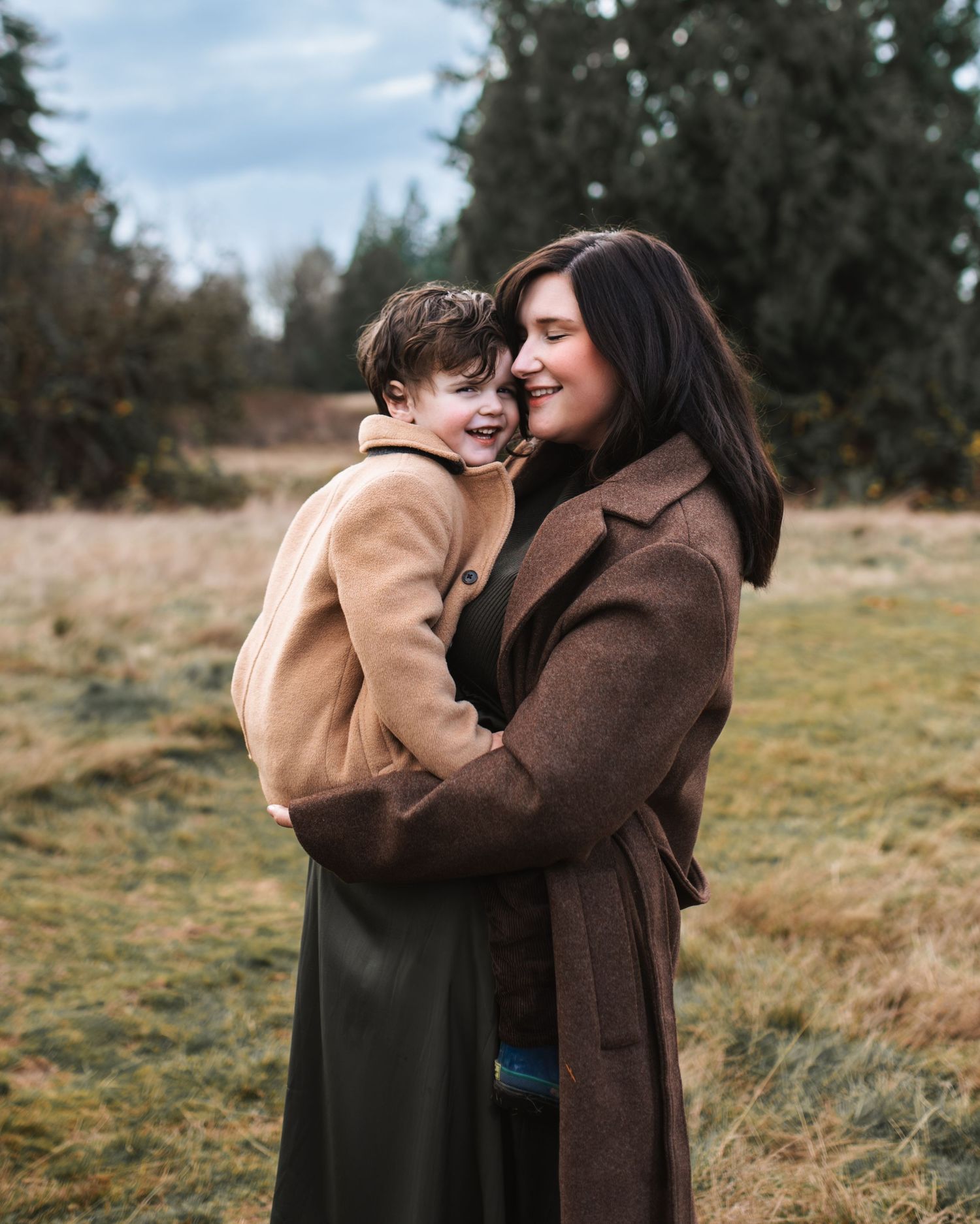 toddler boy snuggles into pregnant mom