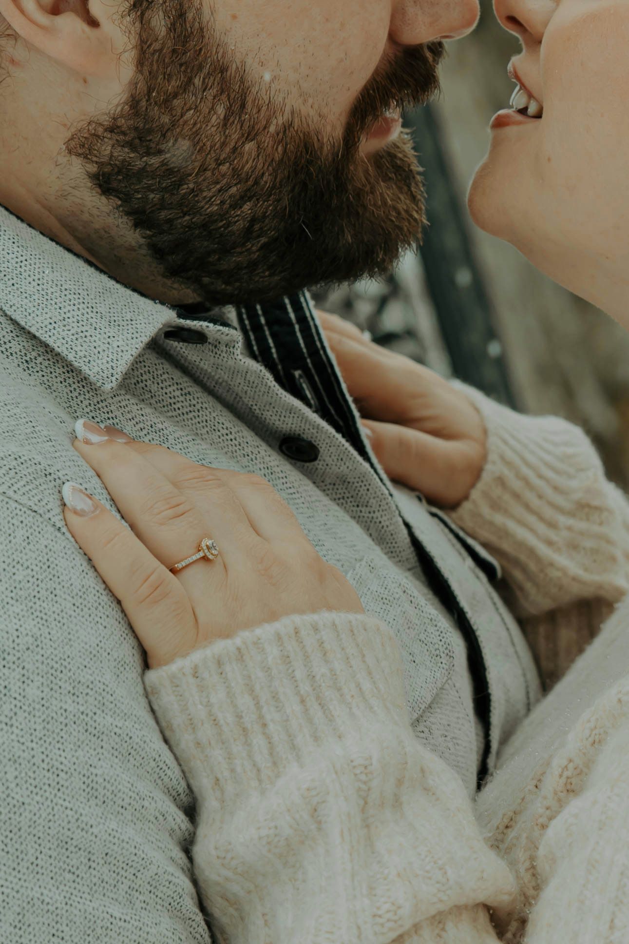 Close-up view of a person wearing a cozy cream knit sweater and dark jacket in soft, muted lighting.