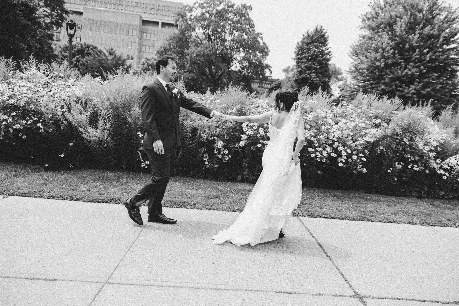 A tender moment between a couple in formal attire dancing outdoors in a garden setting.