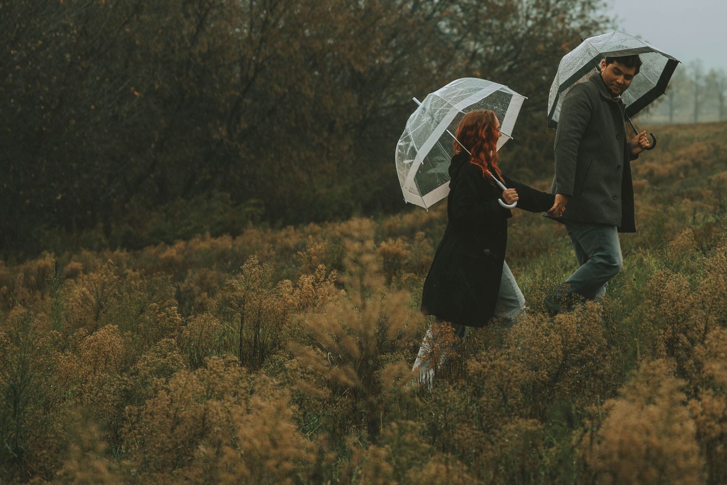 A person holds a white umbrella while walking through an autumn landscape with golden foliage.
