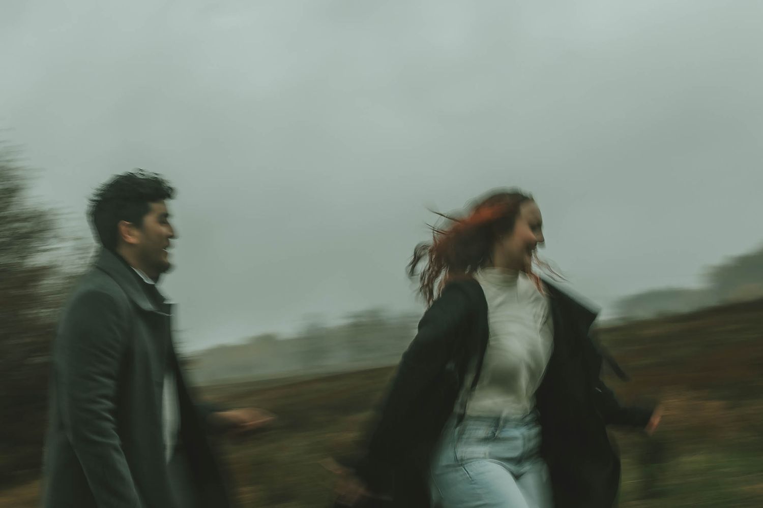 Two people walking outdoors on a moody overcast day with motion blur in the countryside.