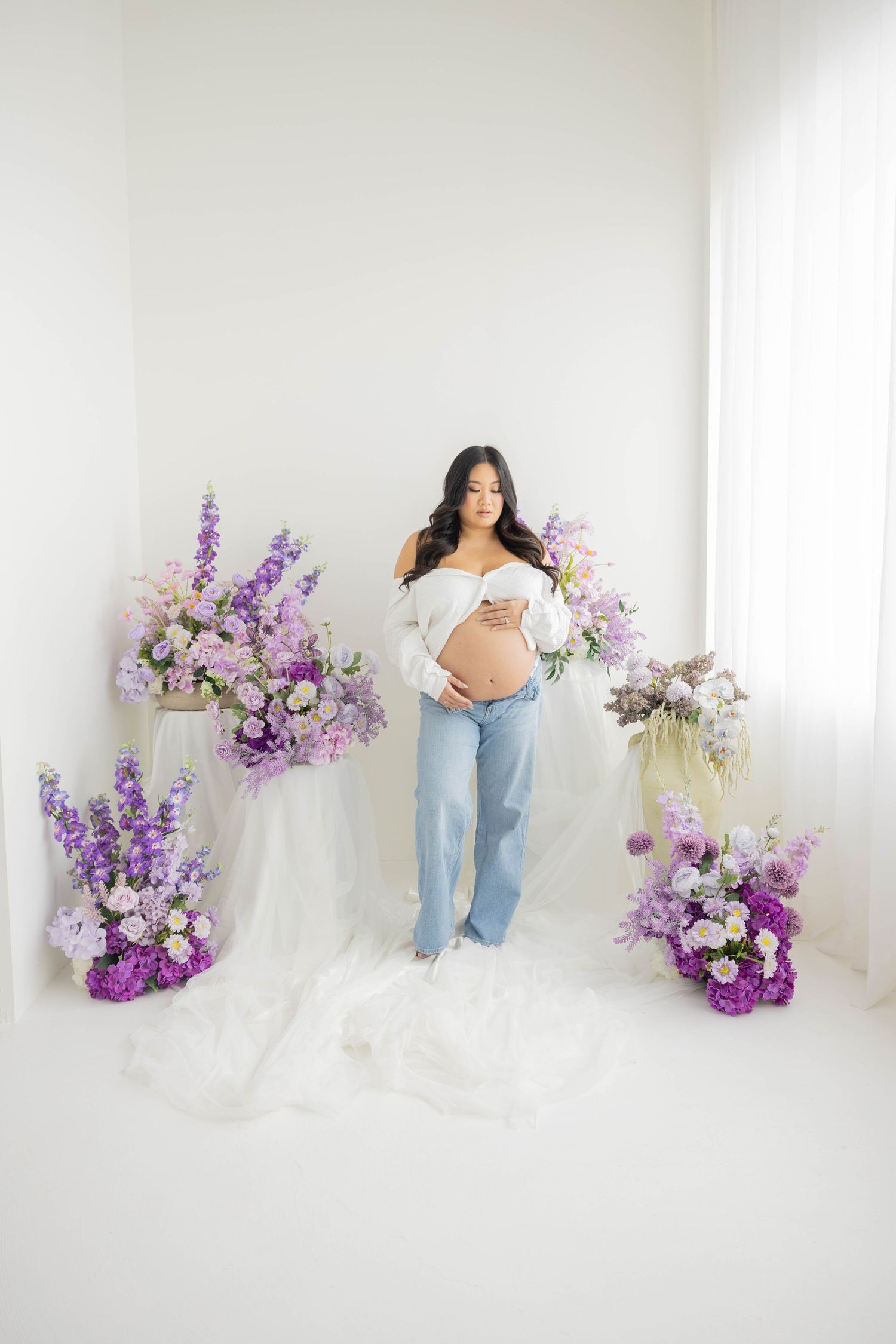 Ethereal portrait session featuring purple and pink floral arrangements against a bright white backdrop.