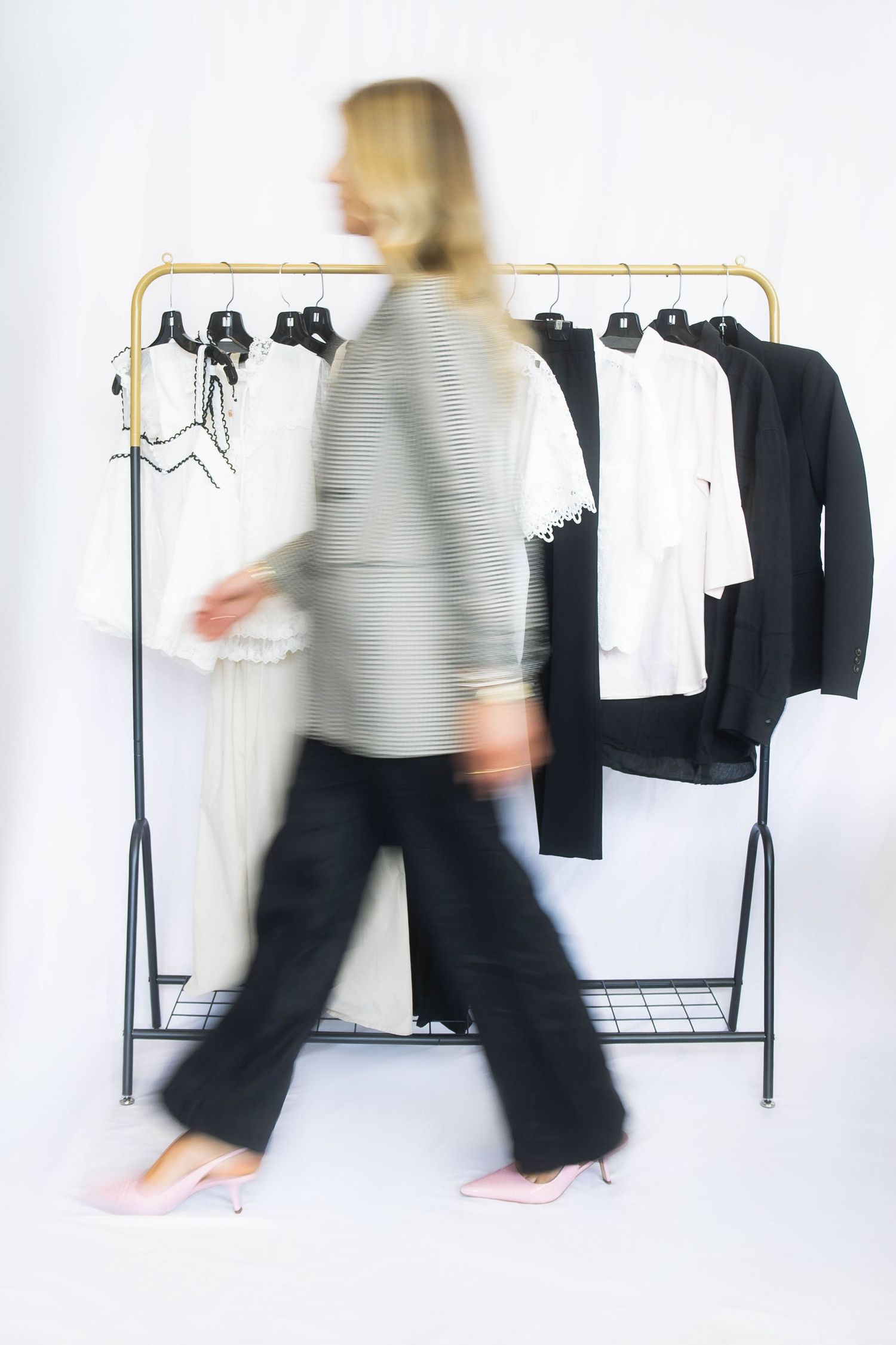 Motion blur sequence of someone walking past a clothing rack with black and white garments.