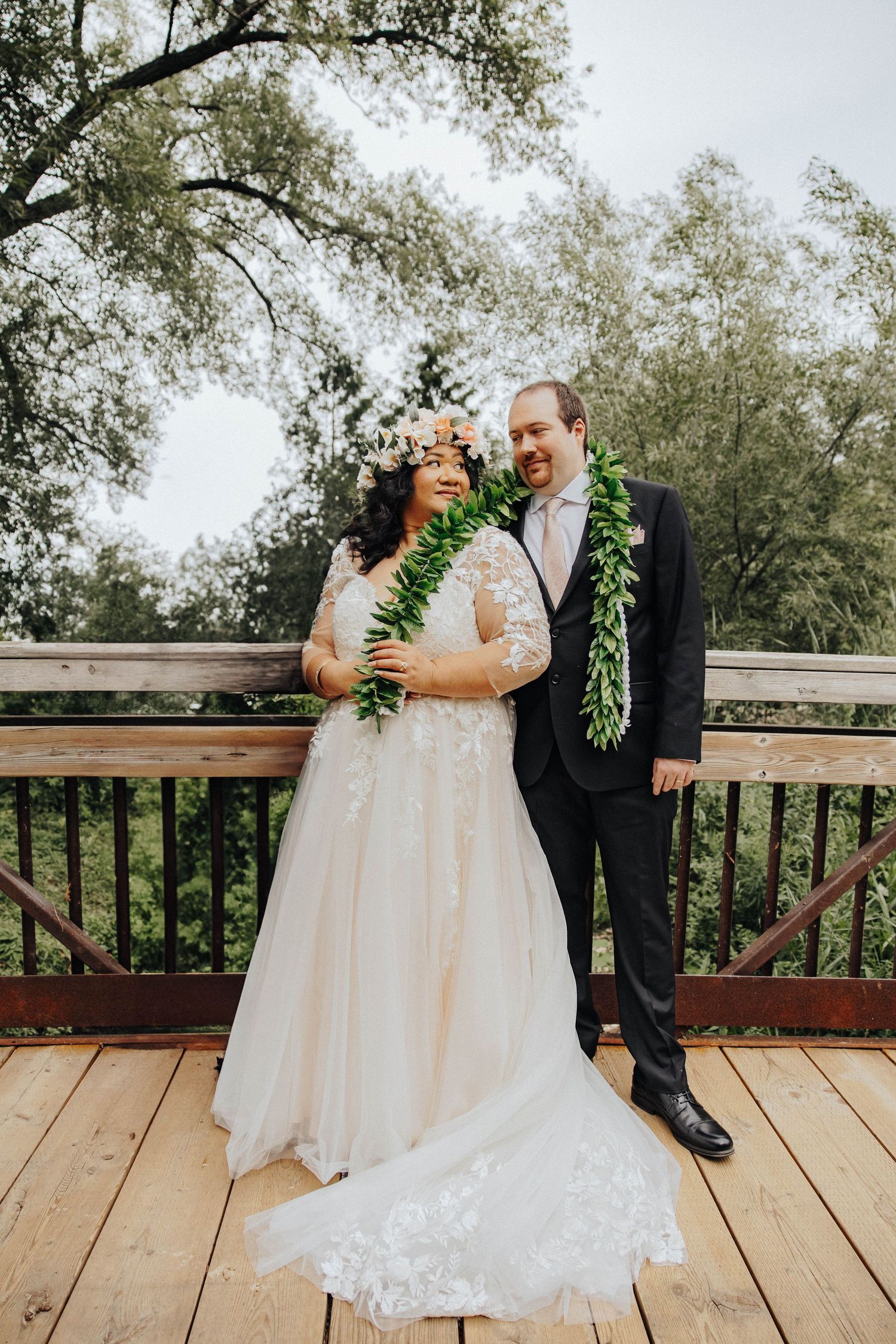 Wedding couple shares romantic moments on wooden deck surrounded by greenery in series of intimate poses.
