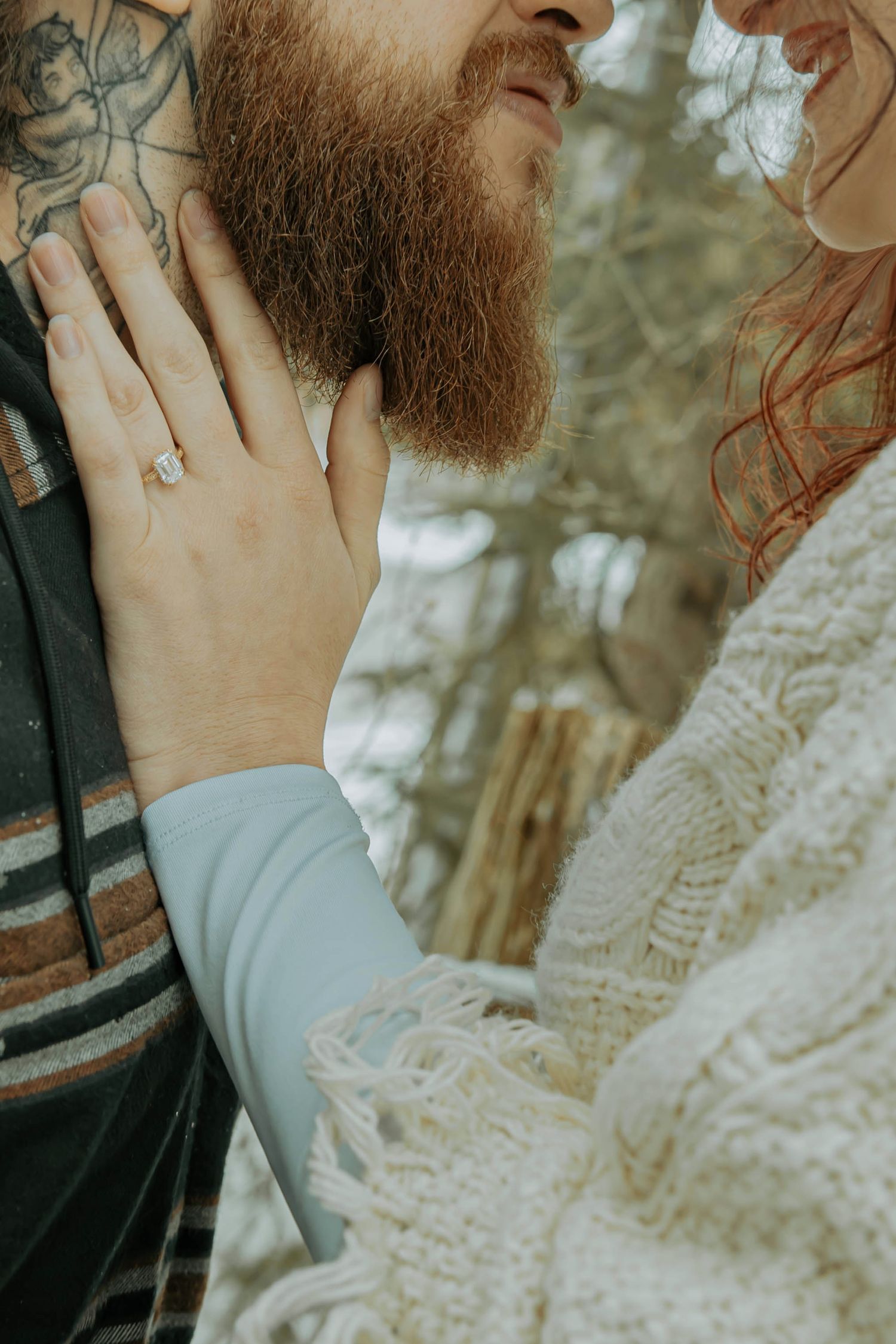 Close-up shot of hands touching a bearded person wearing a striped sweater and someone in a white lace dress.