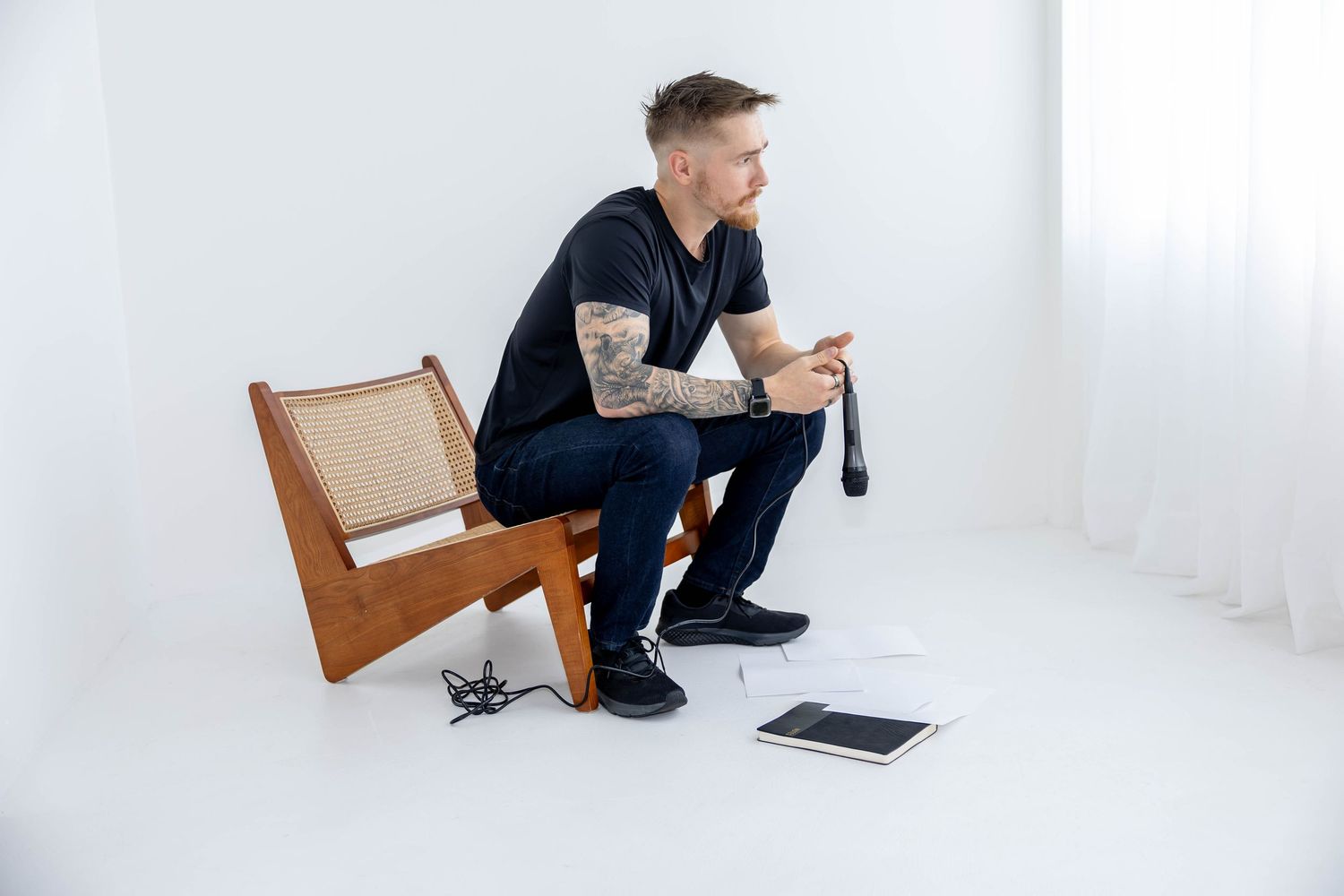 Person in casual attire sitting on floor against white wall with digital devices nearby.