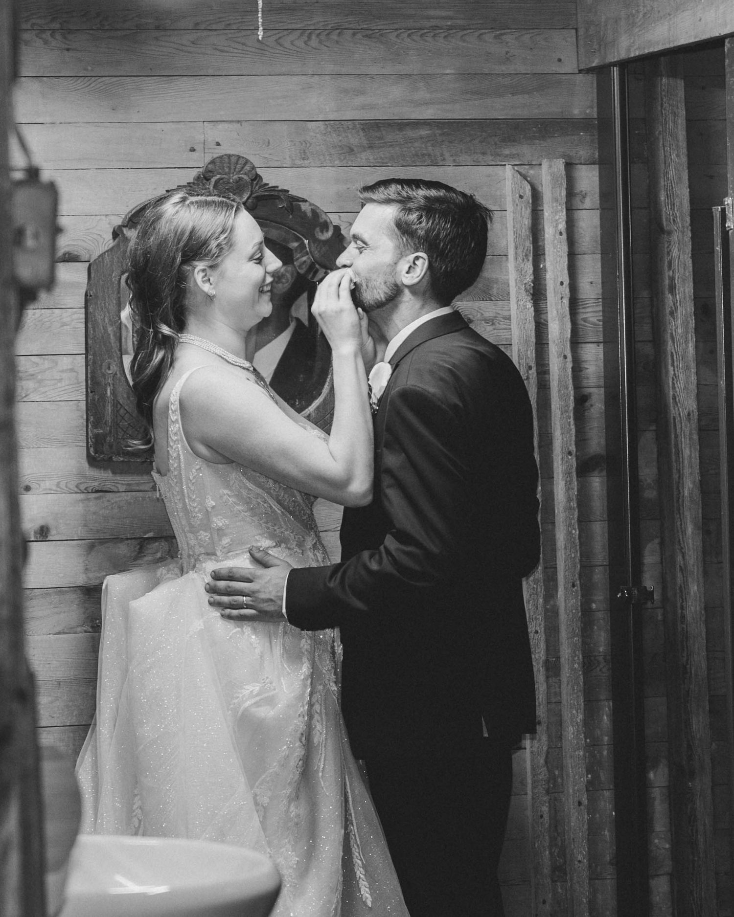 Black and white wedding photo collage showing romantic moments between newlyweds in a rustic wooden setting.