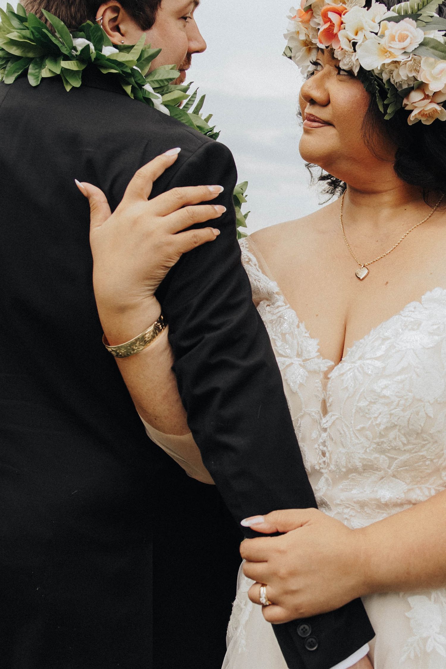 Romantic close-up shots showing a bride in white lace and groom in black suit embracing during their wedding photoshoot.