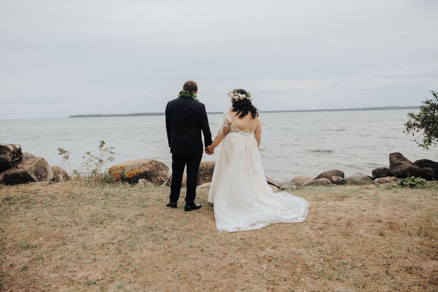 Two people stand together at a scenic coastal overlook during what appears to be a formal occasion.