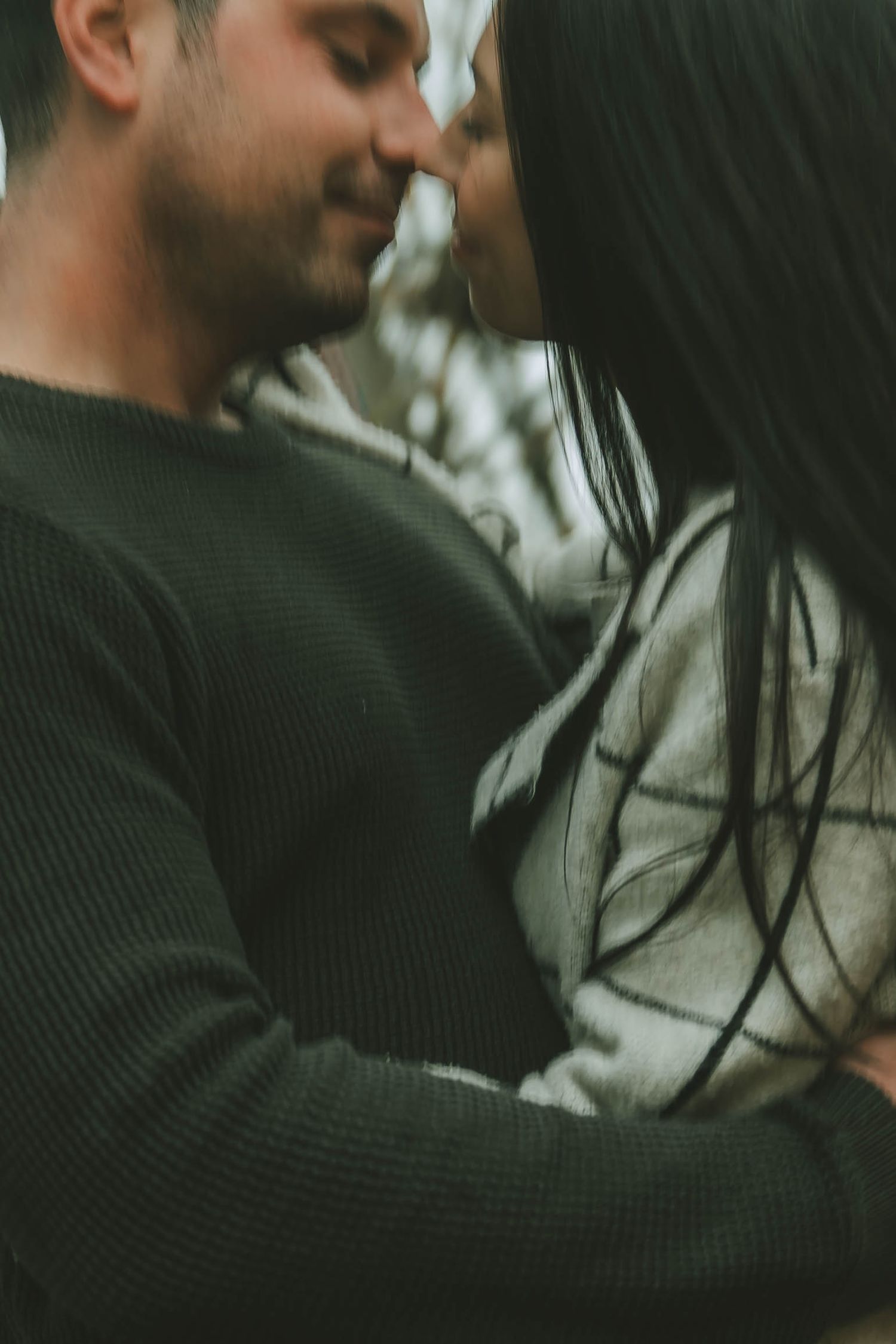 A series of intimate close-up shots showing two people in dark clothing sharing a tender moment.