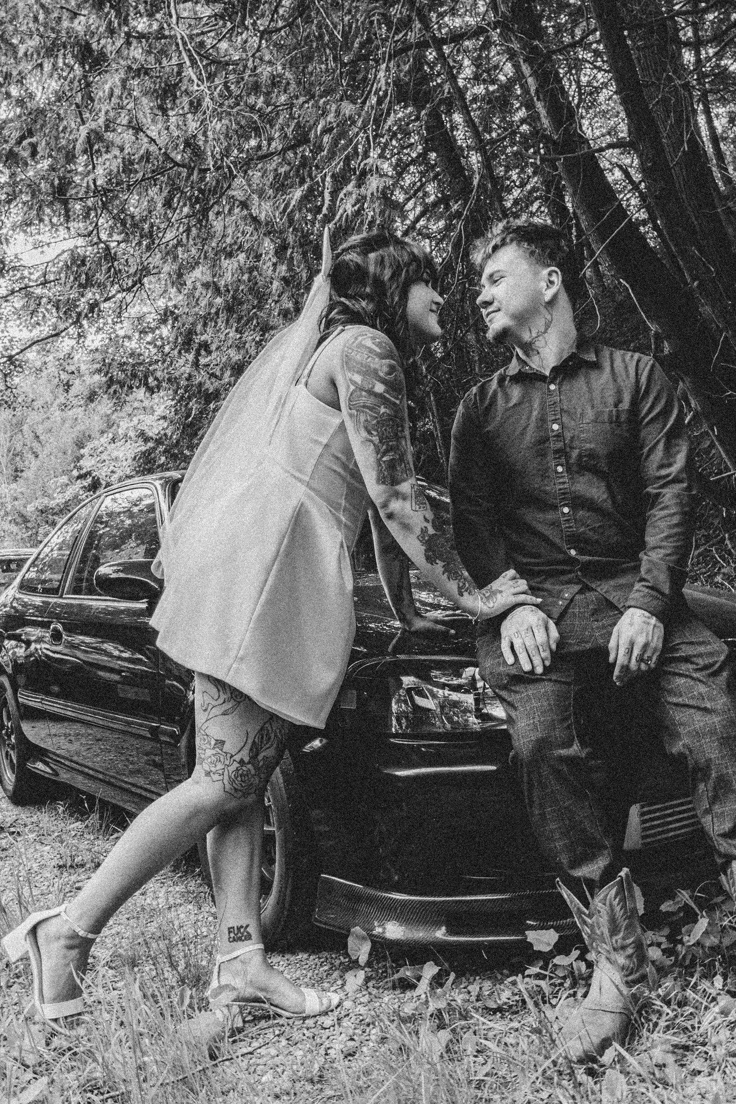 Black and white photography series showing a couple seated on a vintage car in nature.