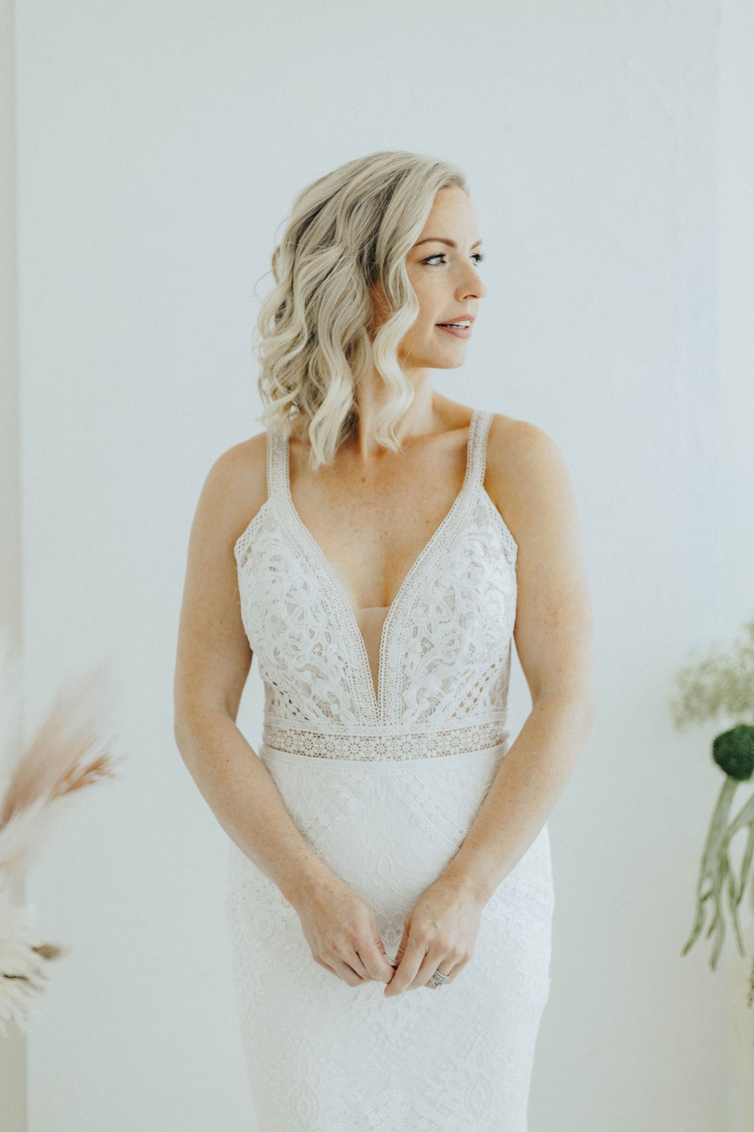 A detail collage of a white lace wedding dress featuring plunging neckline and intricate beadwork in natural lighting.