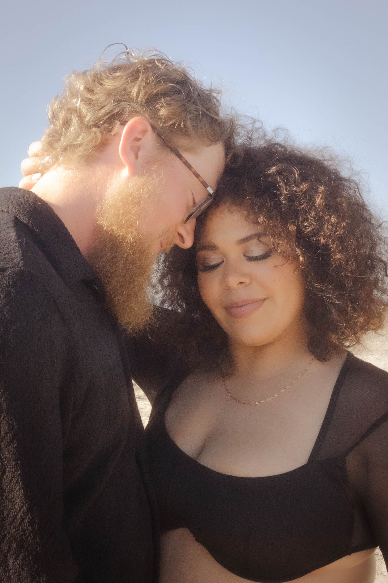 A romantic backlit portrait of a couple sharing an intimate moment, with soft lighting creating a dreamy atmosphere.