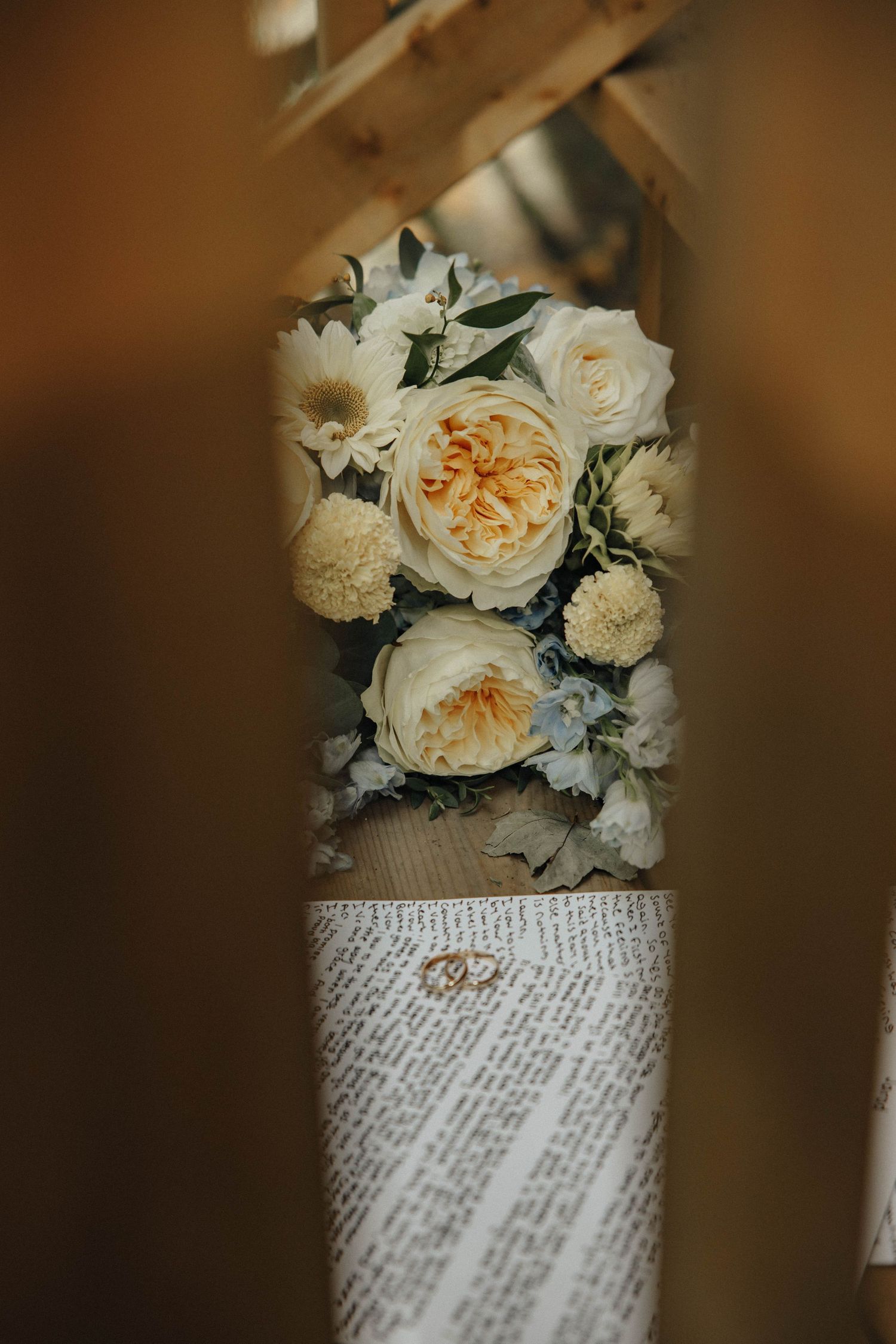 Elegant white roses and flowers wrapped in newspaper create a vintage-inspired wedding bouquet display.