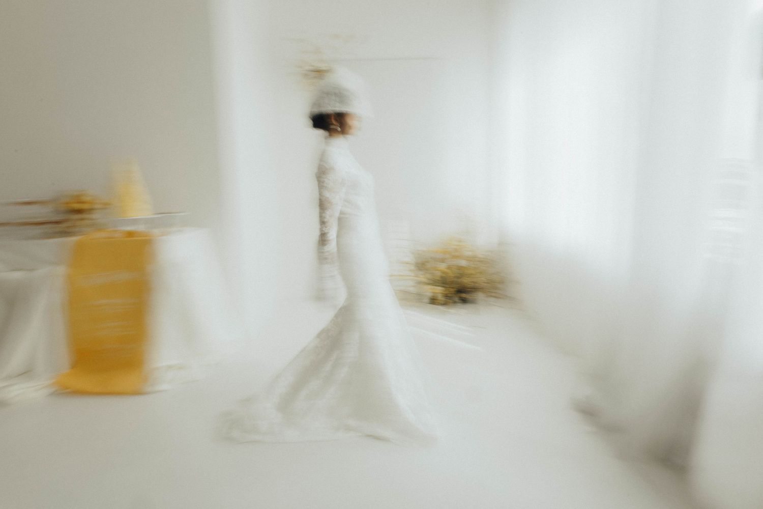 Abstract blurred motion photograph of a figure in white moving through a bright minimalist space.