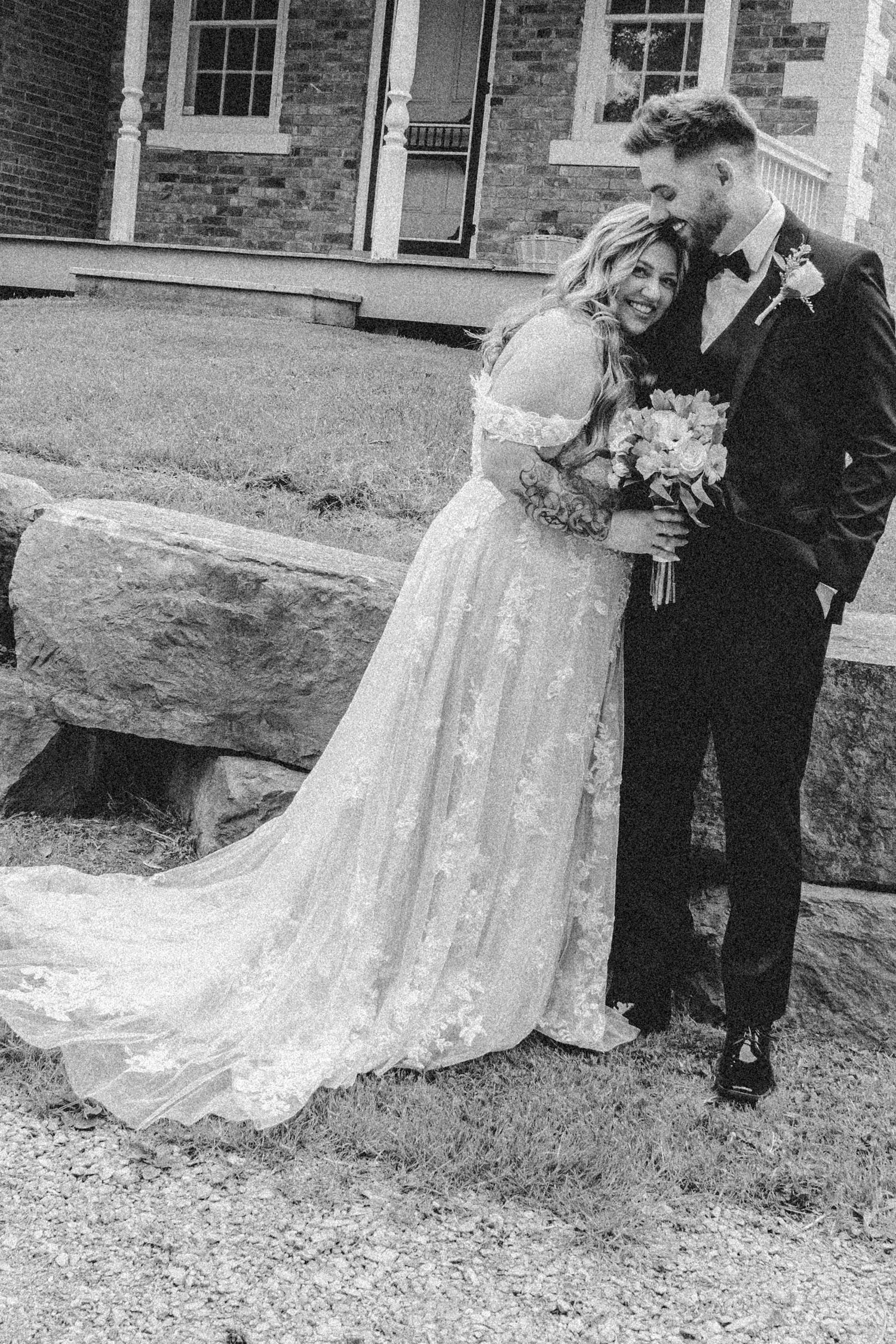 Black and white wedding photos capturing romantic poses against historic brick building.