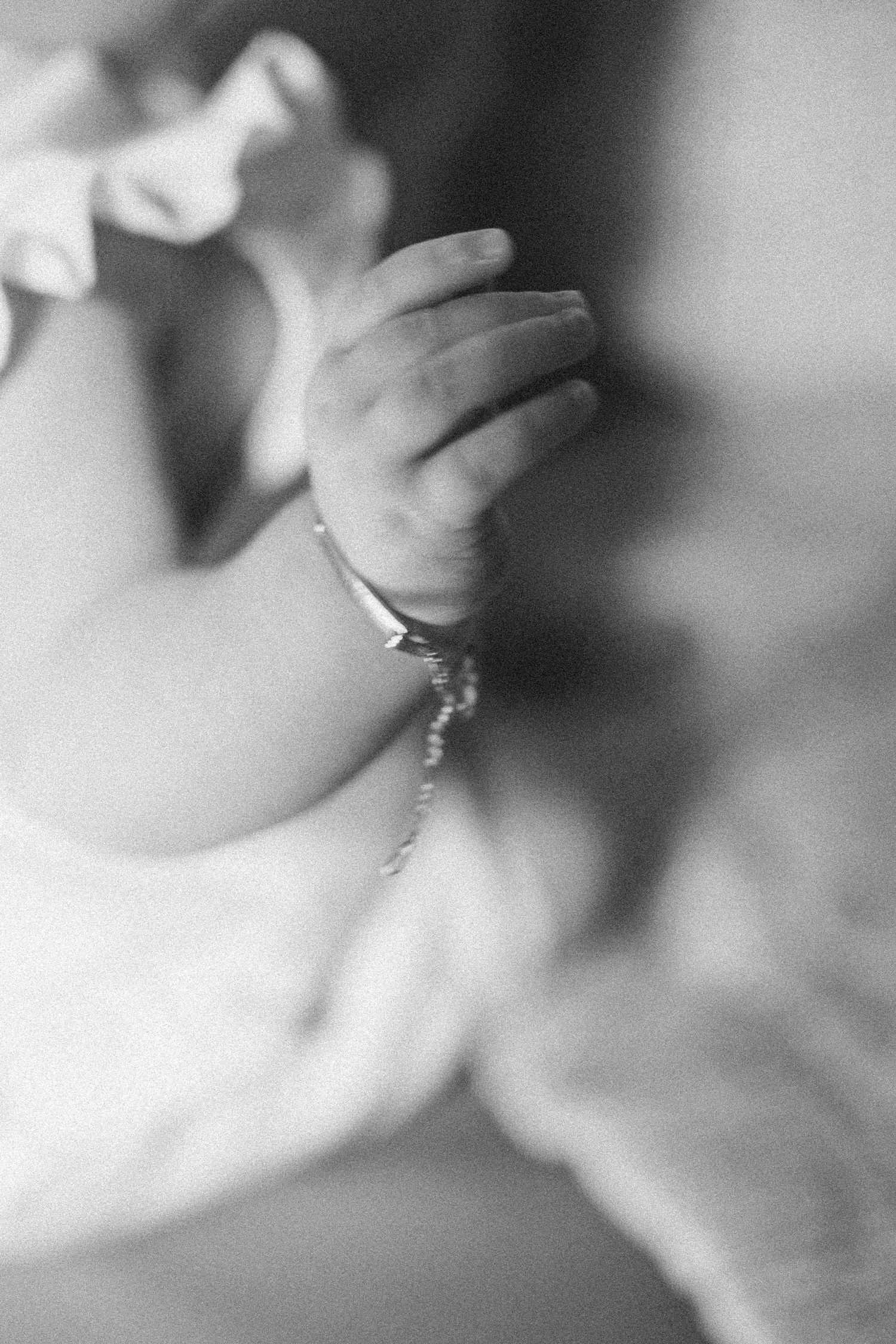 Close-up black and white photo of a baby's tiny hand wearing a delicate bracelet.
