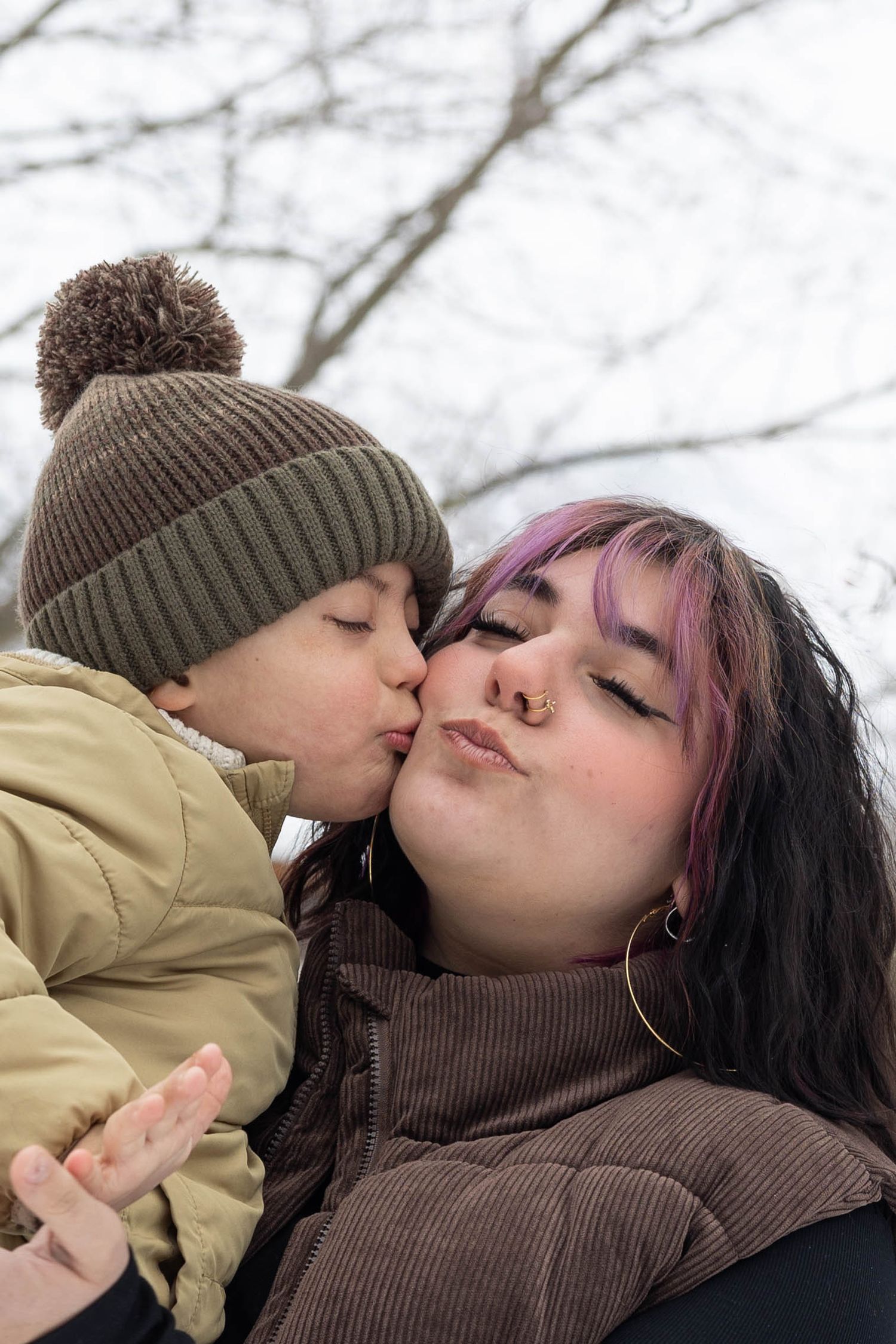 A tender winter kiss sequence captured against a snowy background with bare trees.