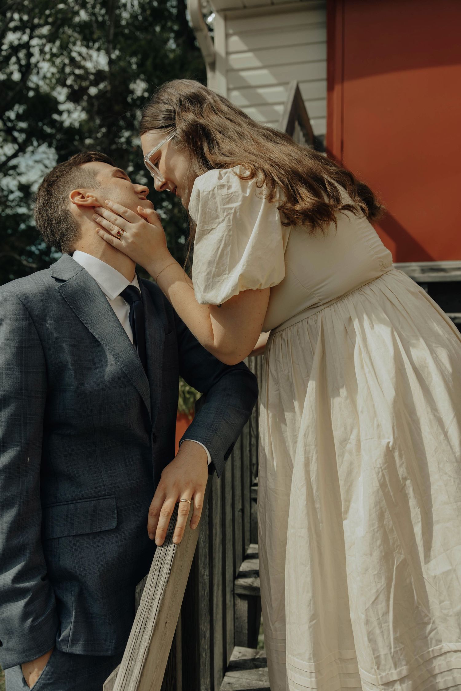 A romantic wedding couple sharing a loving moment on an outdoor wooden deck.