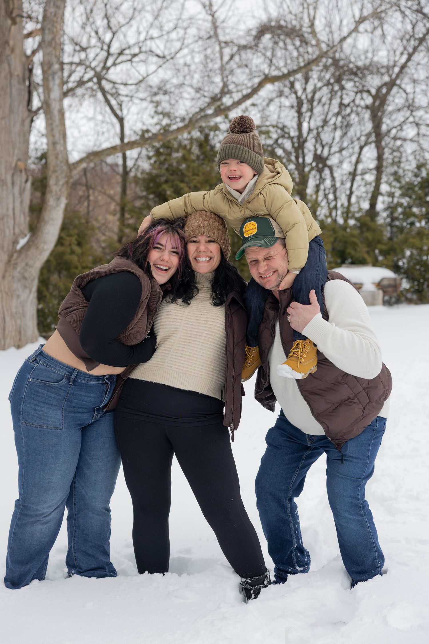 Friends lined up in a playful domino-style pose while standing in snowy winter landscape.
