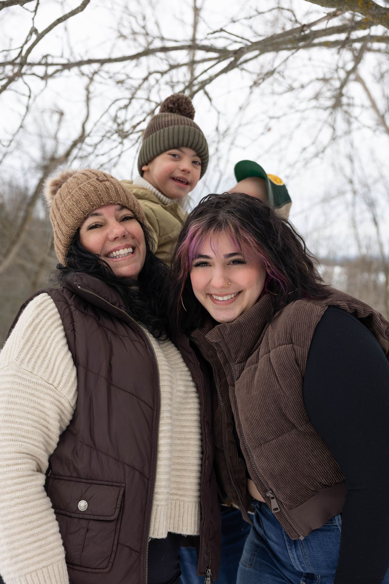 Two people in winter coats and knit hats share a playful moment outdoors during a cold winter day.