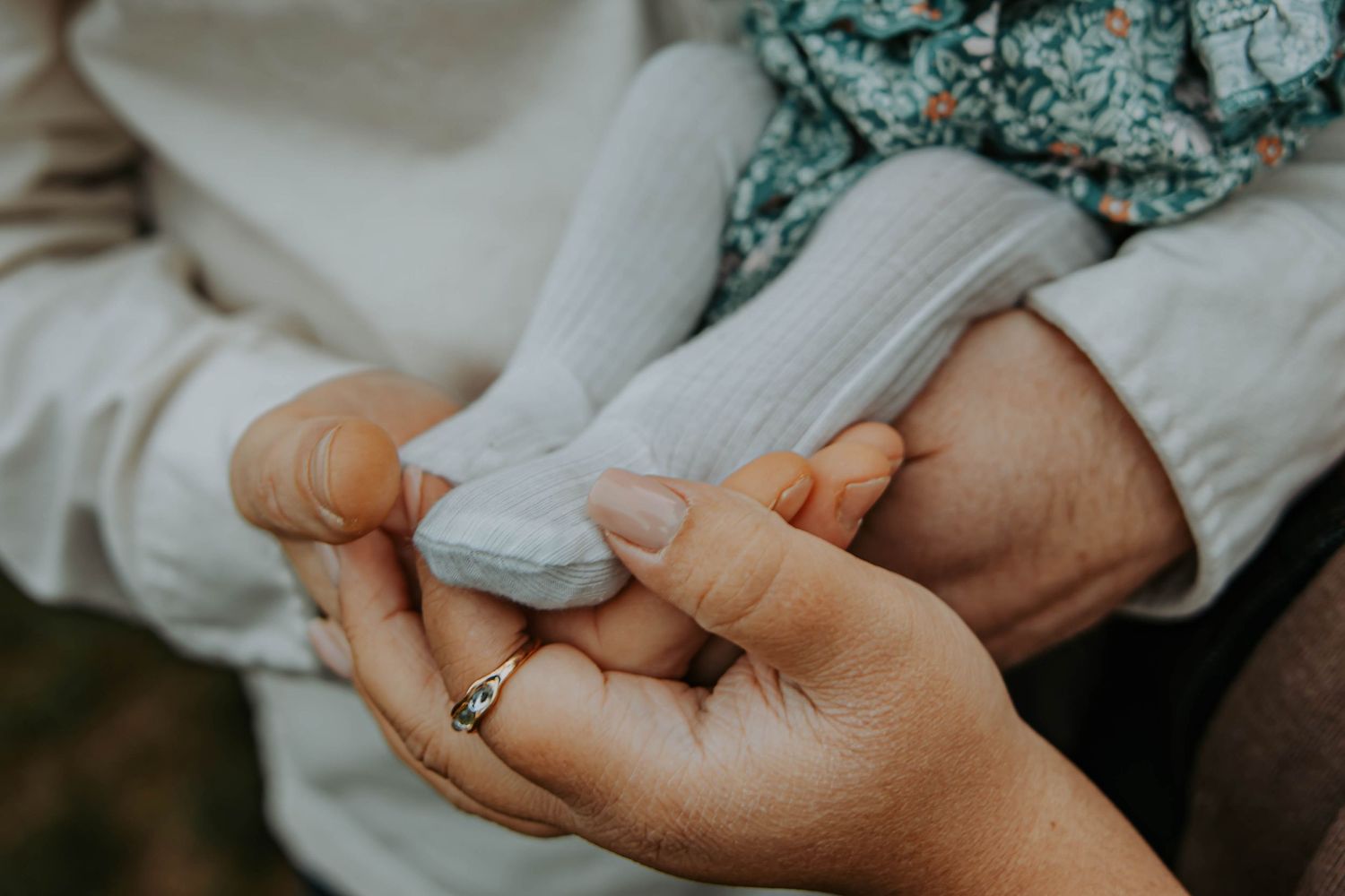 Close-up view of hands holding a baby in soft white blankets during a newborn photography session.