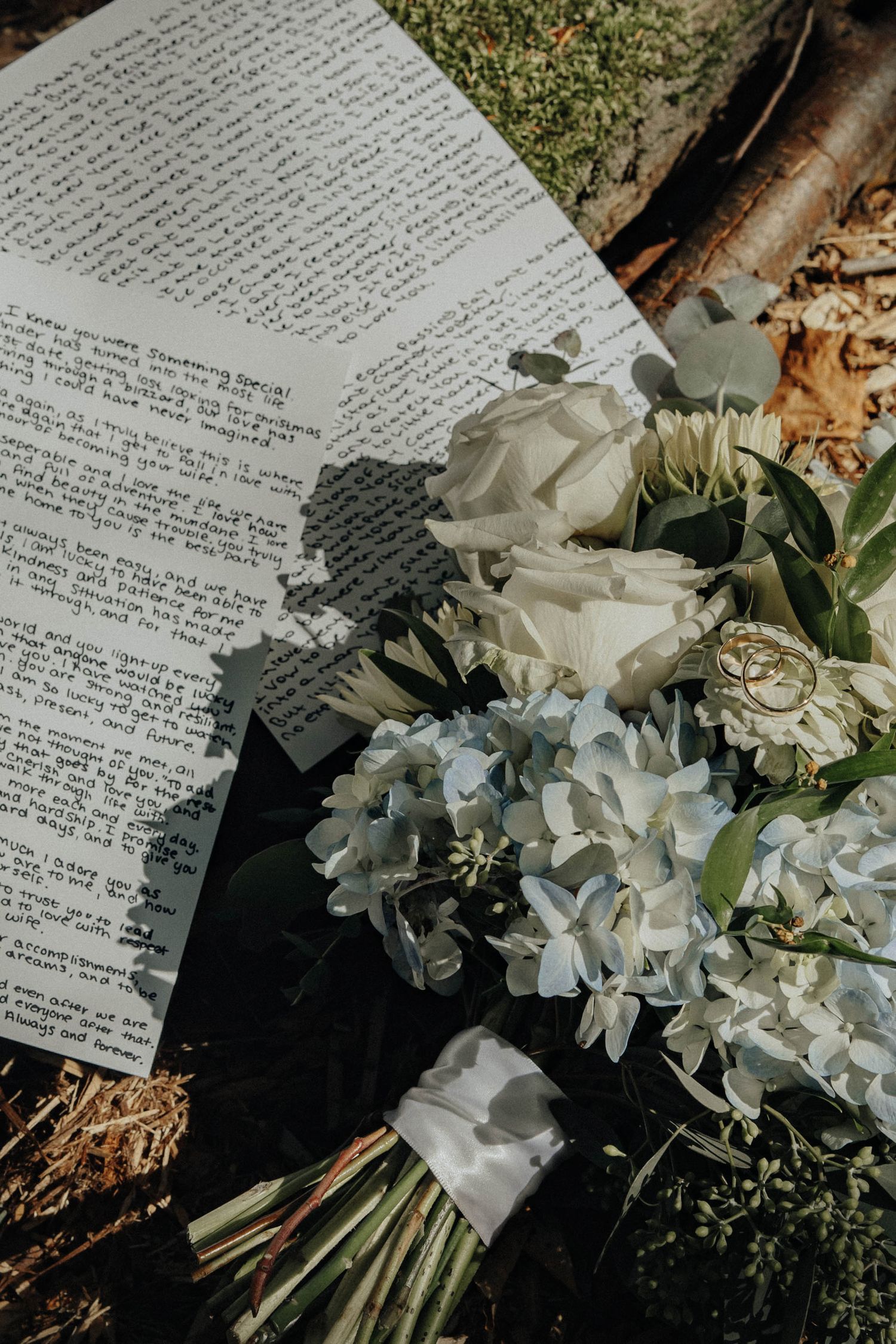 Handwritten letters or vows alongside delicate white hydrangea flowers and greenery in a wedding setting.